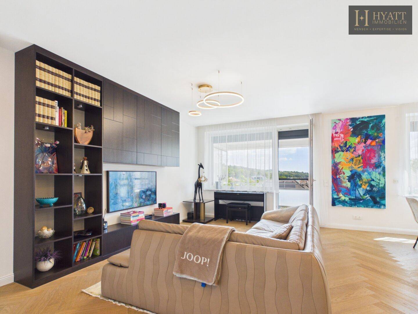 Komfortables Wohnzimmer mit großem Sofa, Einbauregal und weitem Blick durch die Fensterfront.