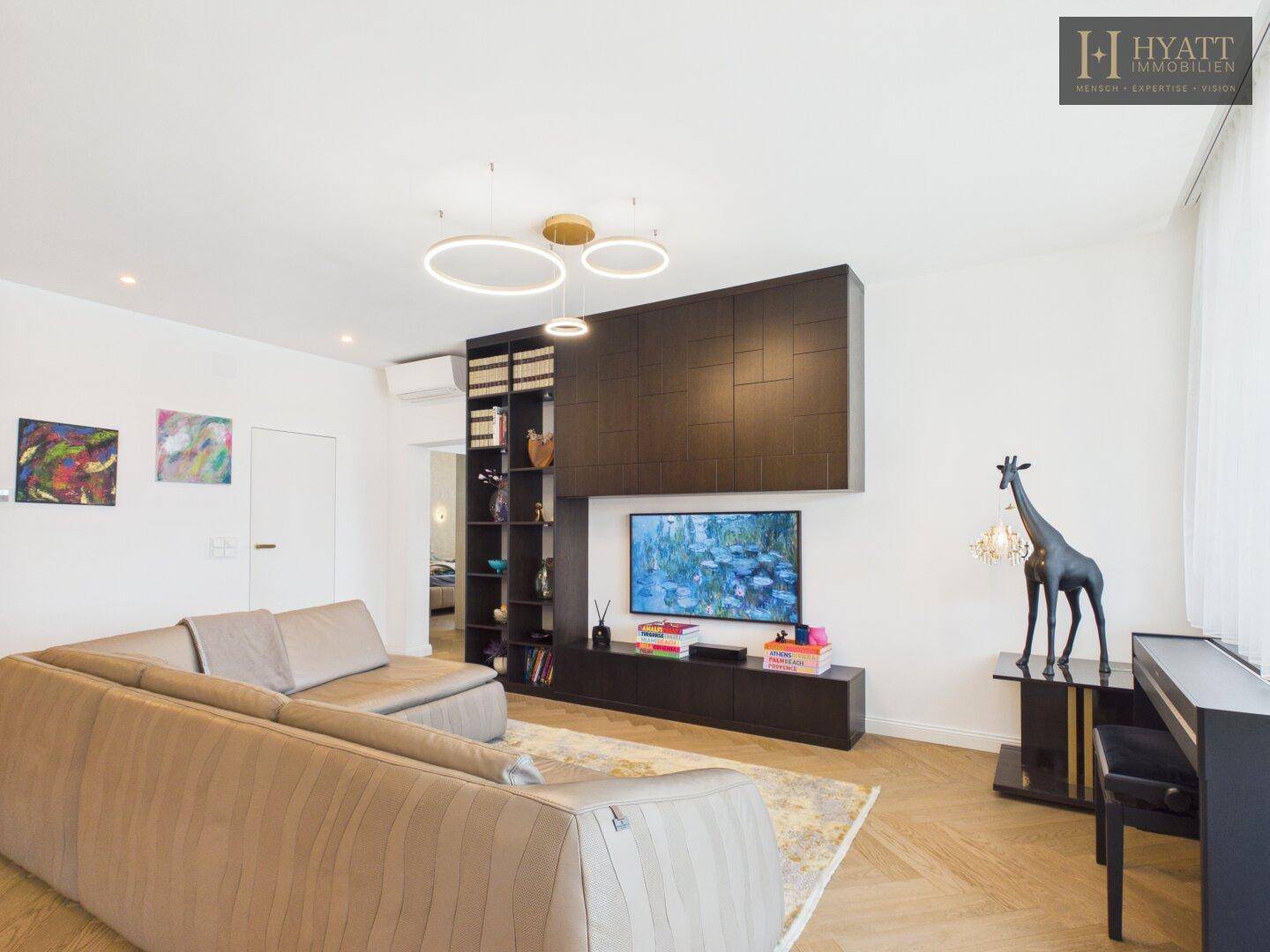 Gemütliches Wohnzimmer mit großem Sofa, Fernseher und stilvollen Einbaumöbeln.