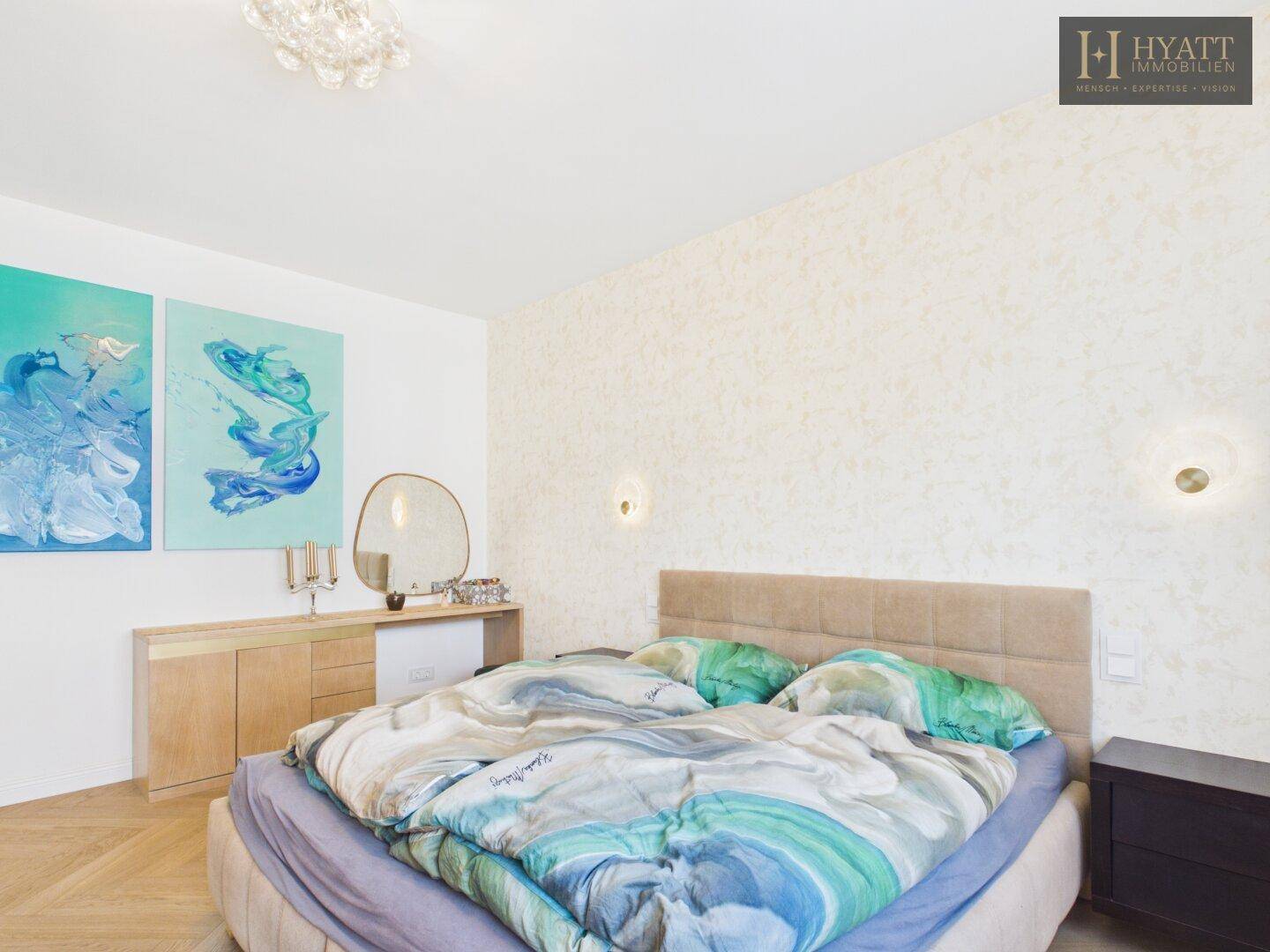 Helles Schlafzimmer mit Doppelbett, Holzboden und moderner Kunst an der Wand.