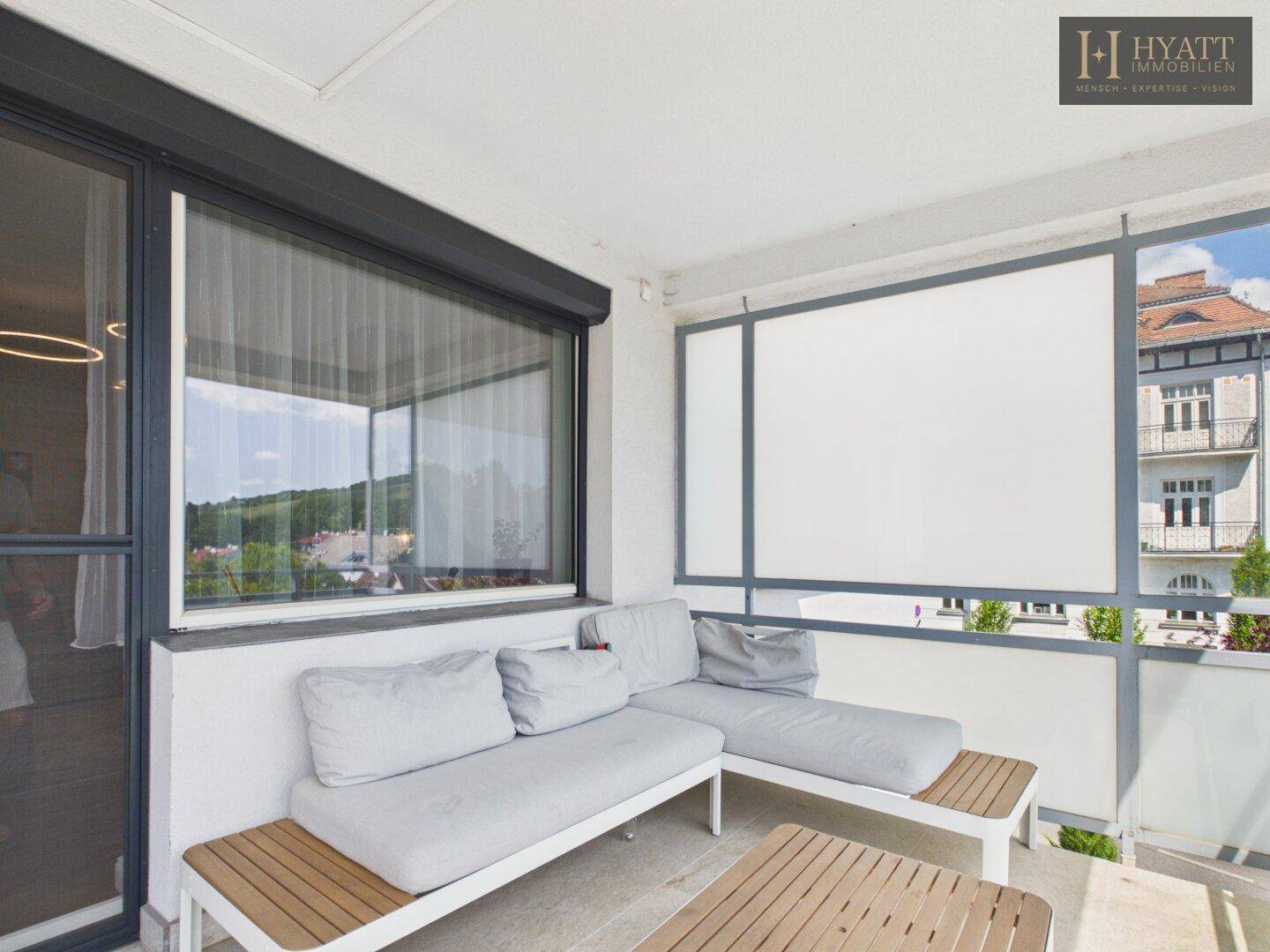 Möblierter Balkon mit bequemen Loungemöbeln und Blick auf die Umgebung.