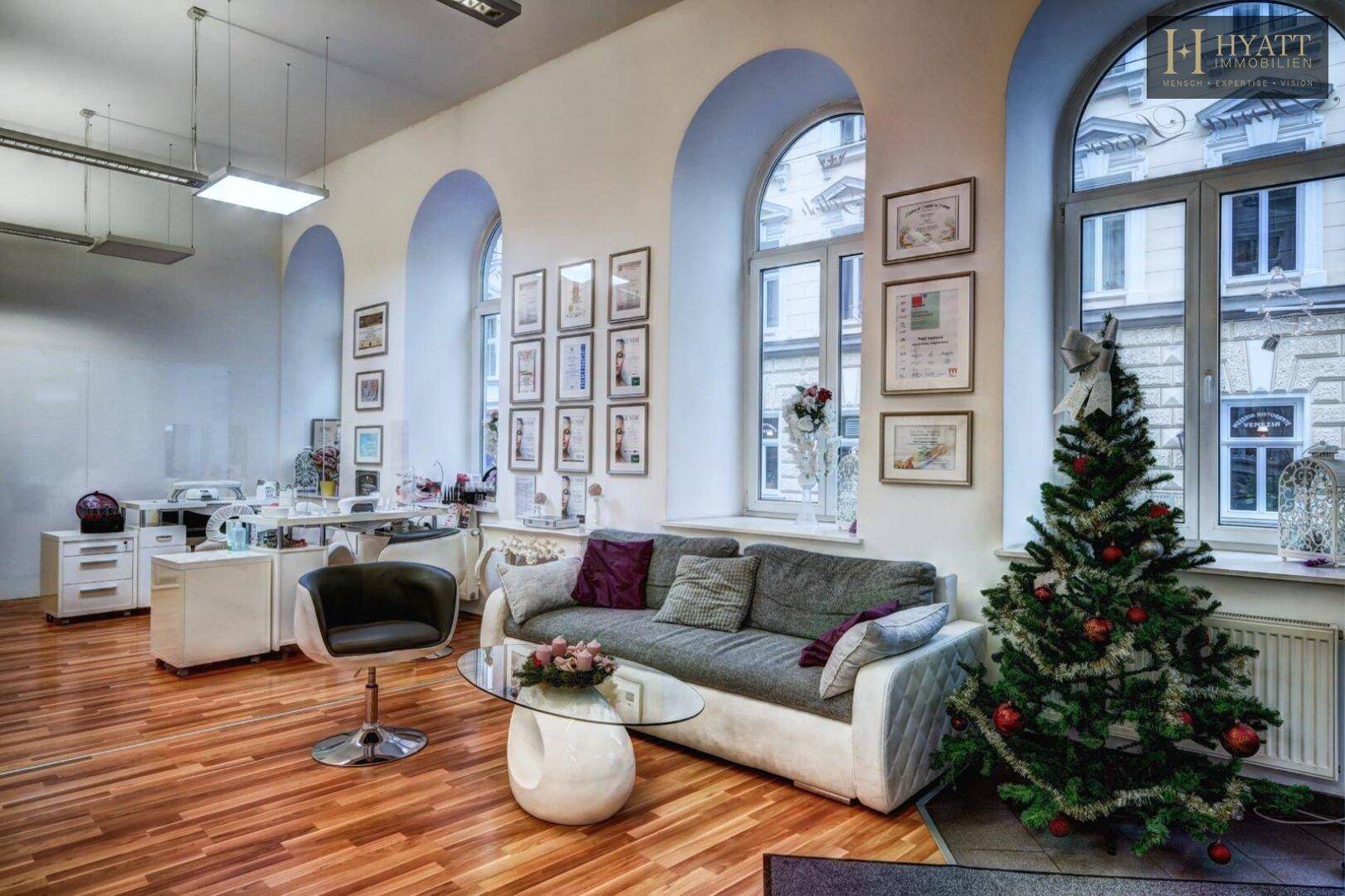 Gemütlicher Loungebereich mit Sofa, Couchtisch und festlicher Weihnachtsdekoration in einem Gewerberaum.