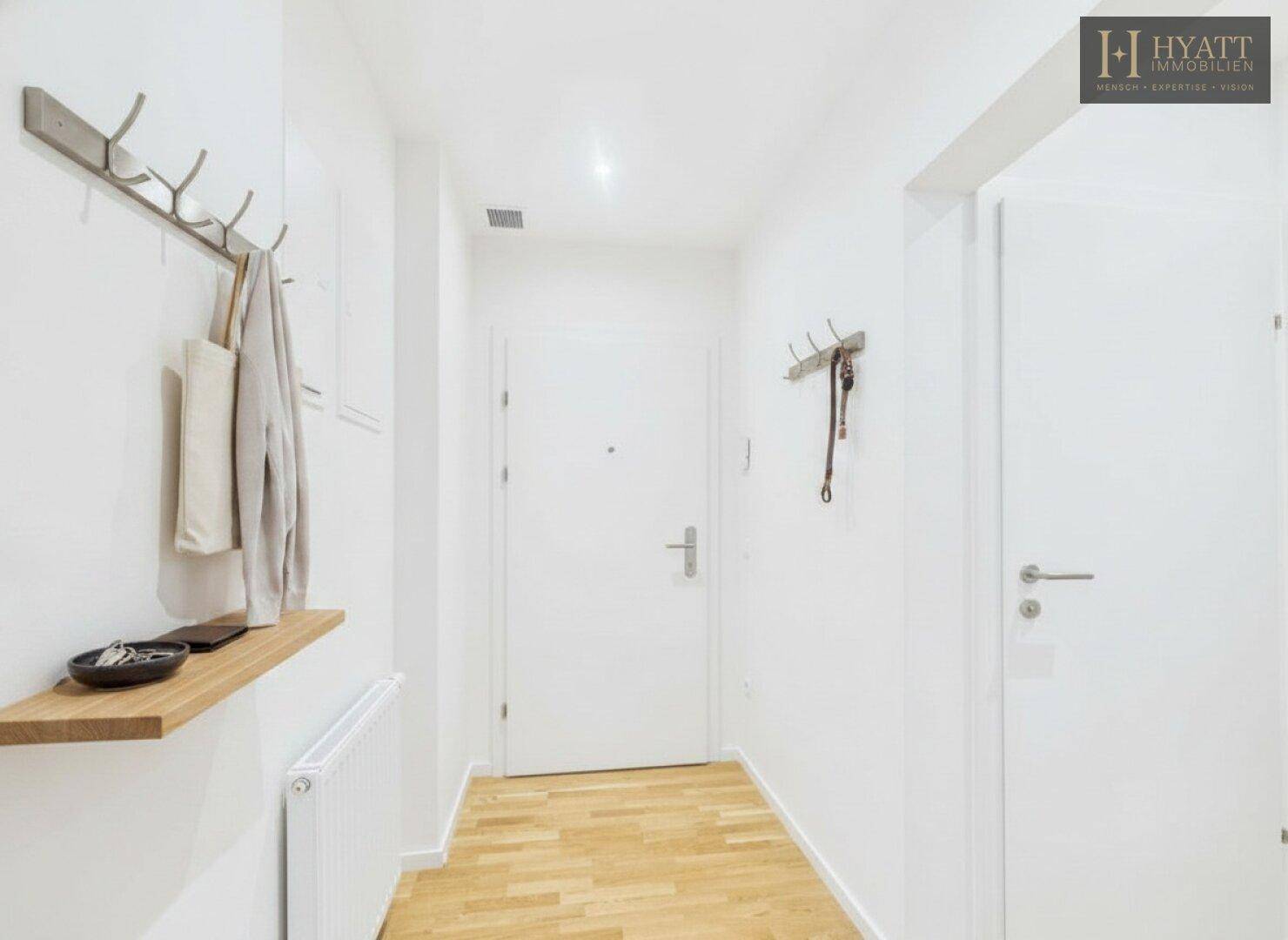 Heller Flur mit Holzboden, weiß gestrichenen Wänden und praktischer Garderobe.