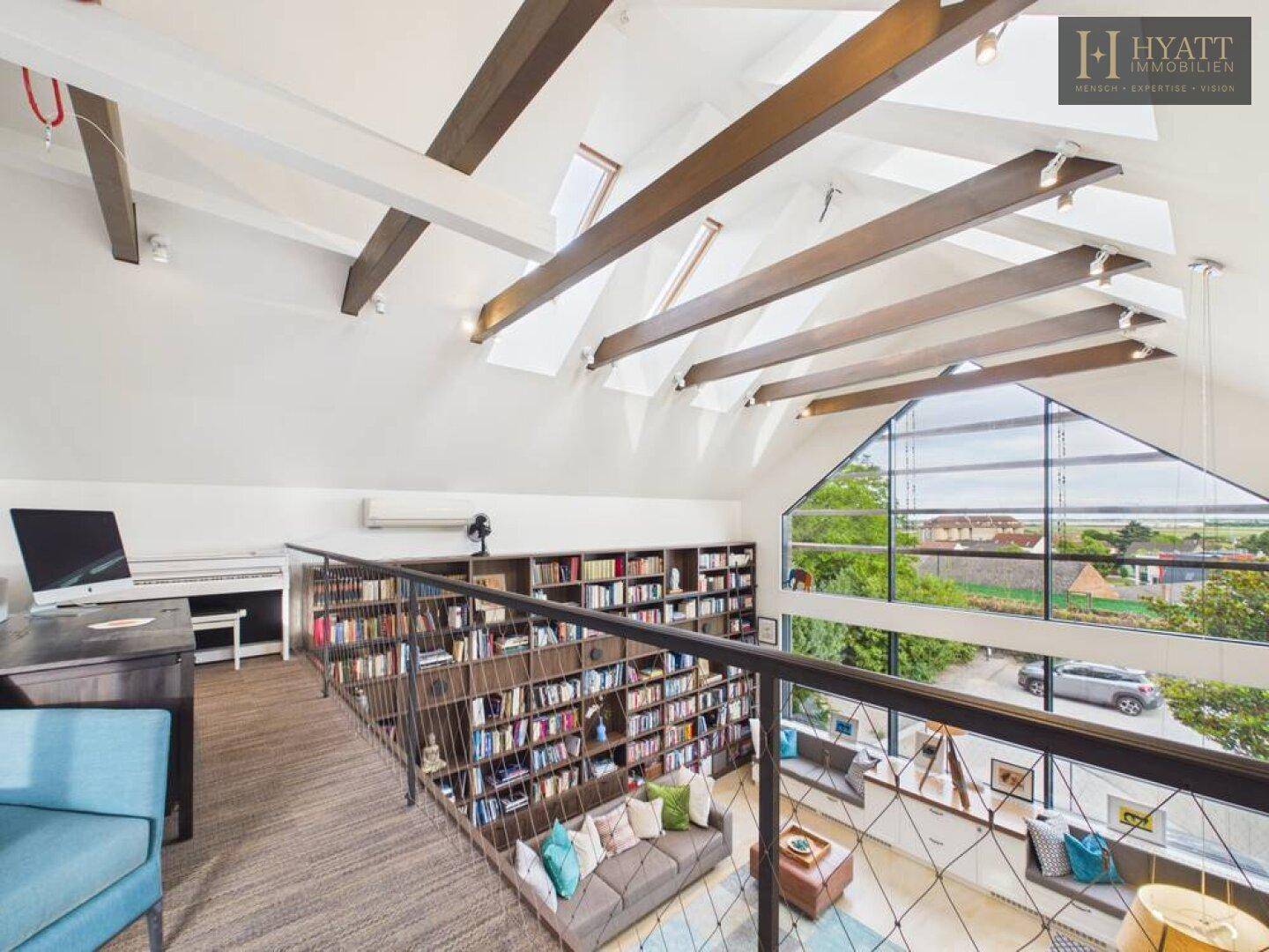 Helle Galerie mit Arbeitsbereich, Klavier und weitem Ausblick über den Wohnraum.
