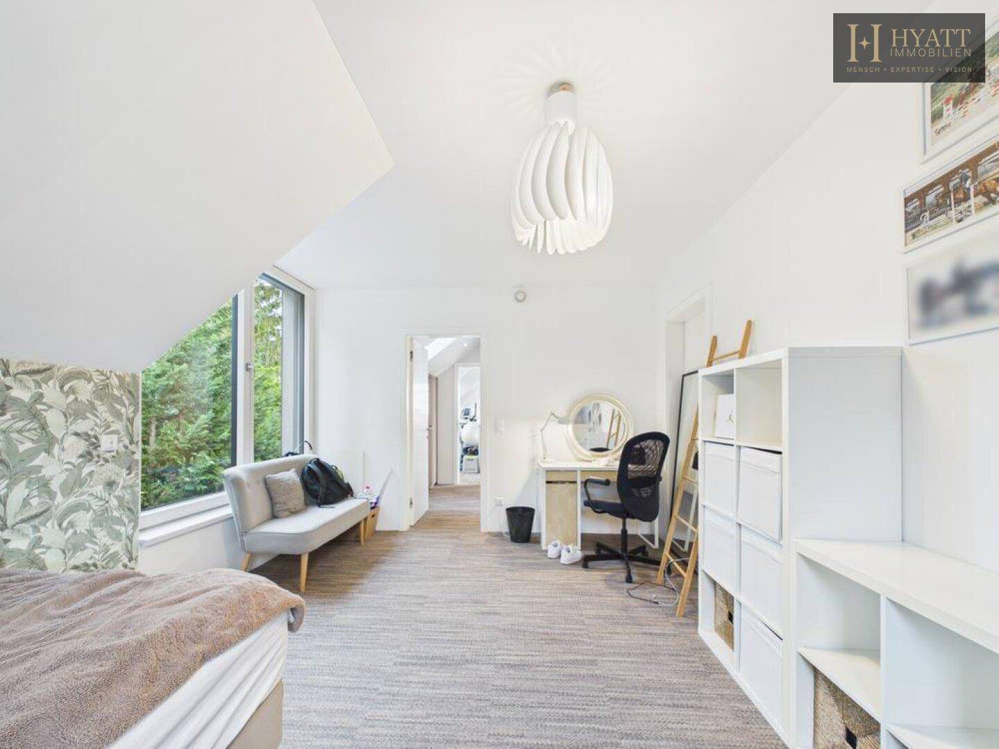 Helles Kinderzimmer mit viel Stauraum, Schreibtisch und Blick auf die umliegende Natur.
