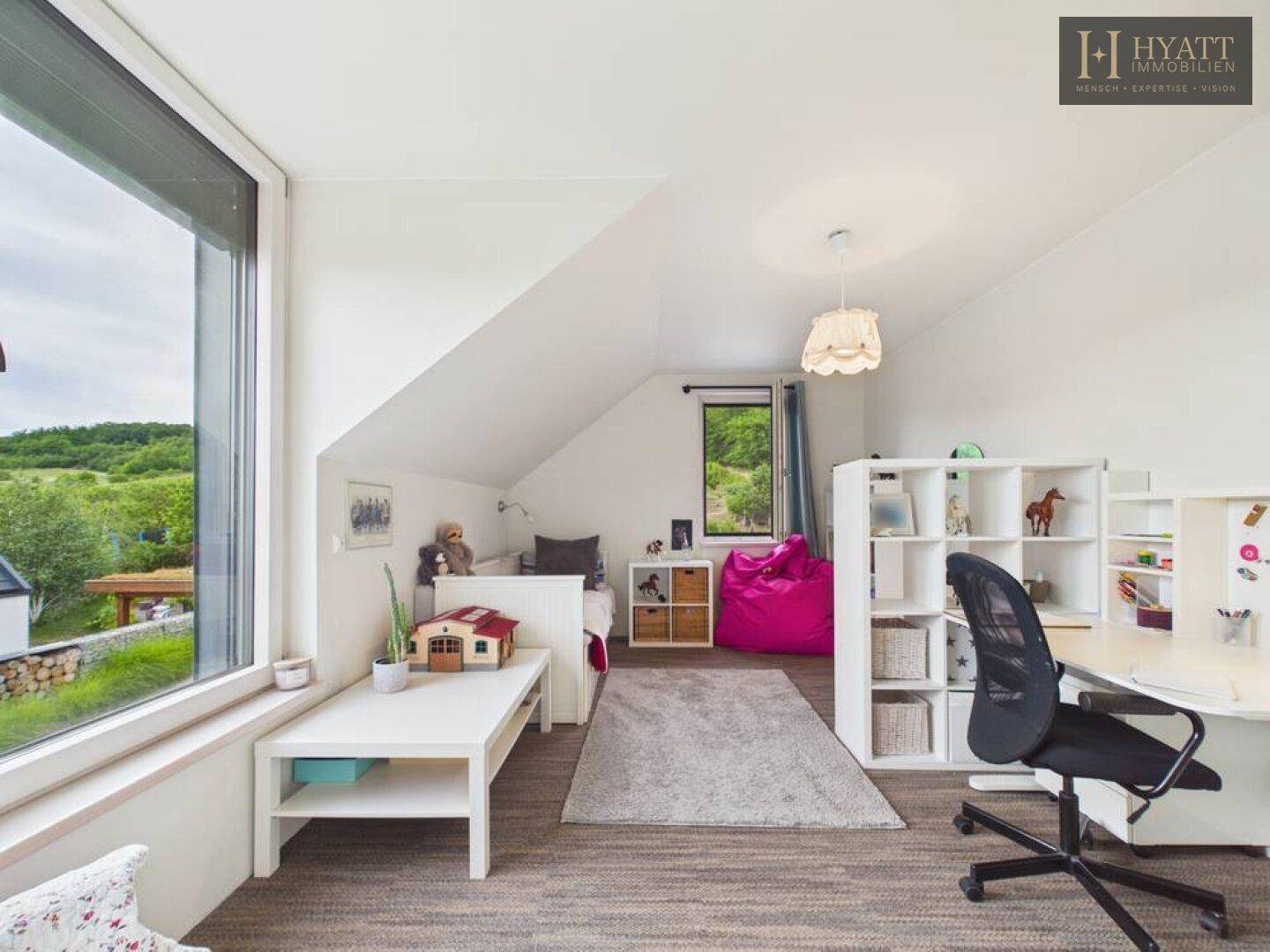 Freundliches Kinderzimmer mit Spielbereich, Schreibtisch und weitem Blick in die Landschaft.