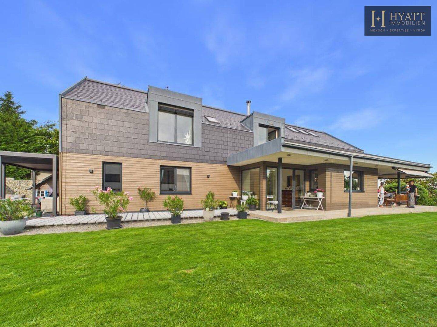Modernes Einfamilienhaus mit Holzfassade, großem Garten und weitläufiger Terrasse.