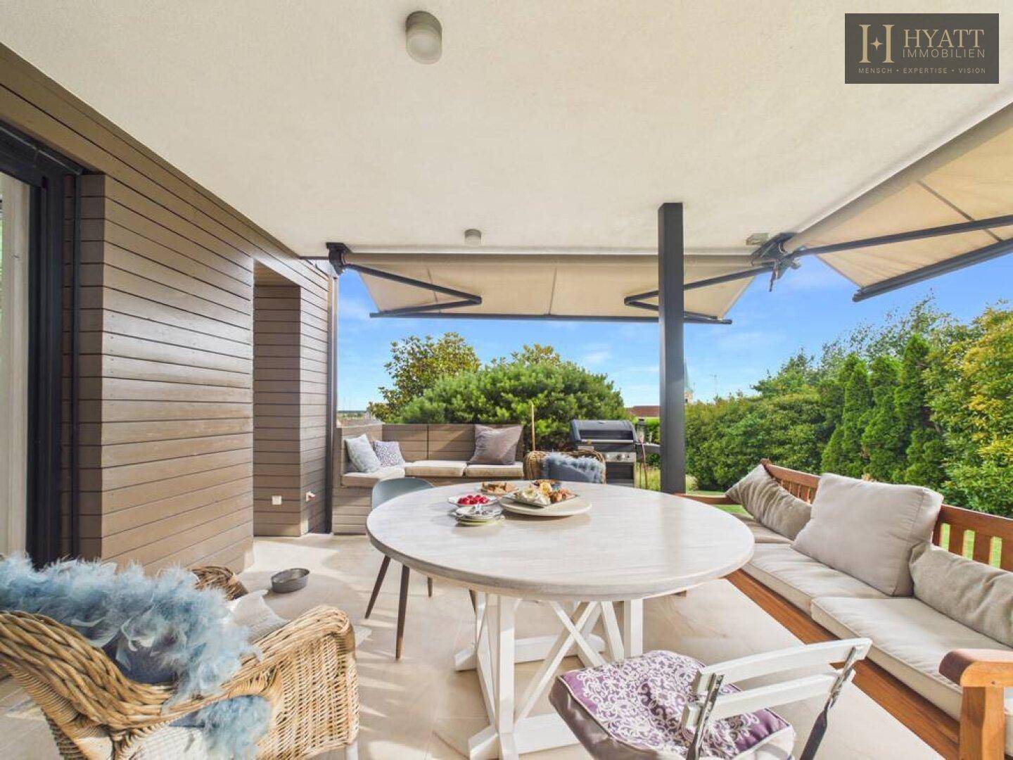 Gemütliche überdachte Terrasse mit Esstisch, Sitzbänken und Grillbereich, ideal für Mahlzeiten im Freien.
