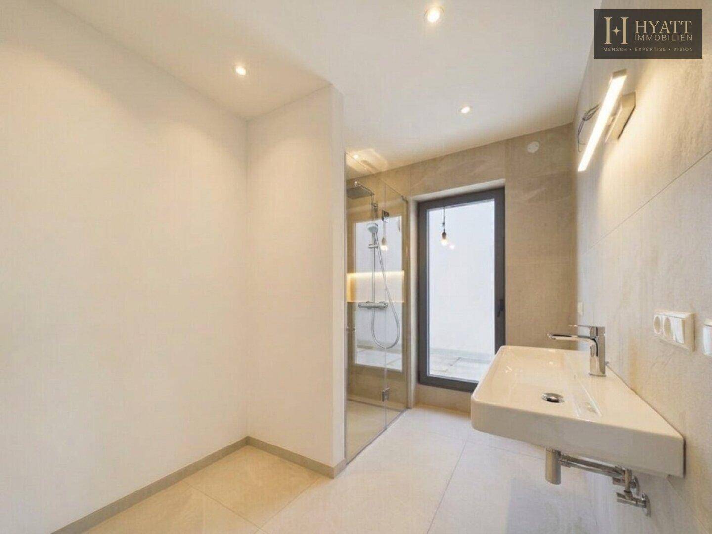 Modernes Badezimmer mit begehbarer Dusche, Doppelwaschbecken und indirekter Beleuchtung.
