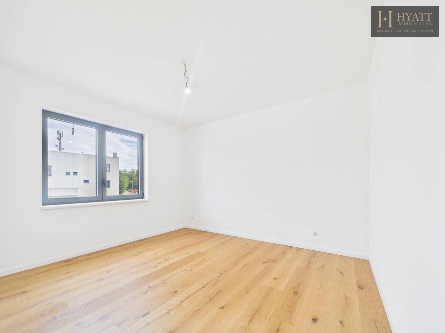 Helles Schlafzimmer mit Eichenparkett und großen Fenstern, die viel Tageslicht bieten.