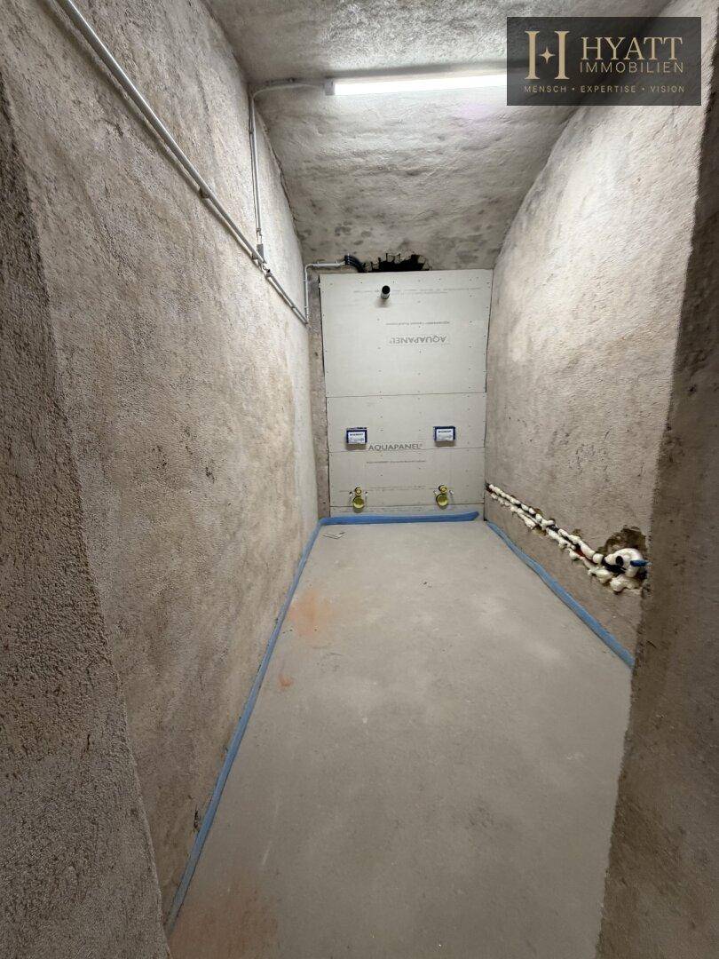 Kellerraum im Rohbau mit sichtbaren Installationen und Betonboden, bereit für den Ausbau.