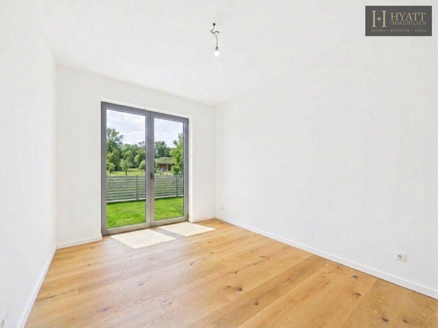 Schlafzimmer mit Holzboden und direktem Zugang zu einem kleinen Außenbereich oder Garten.