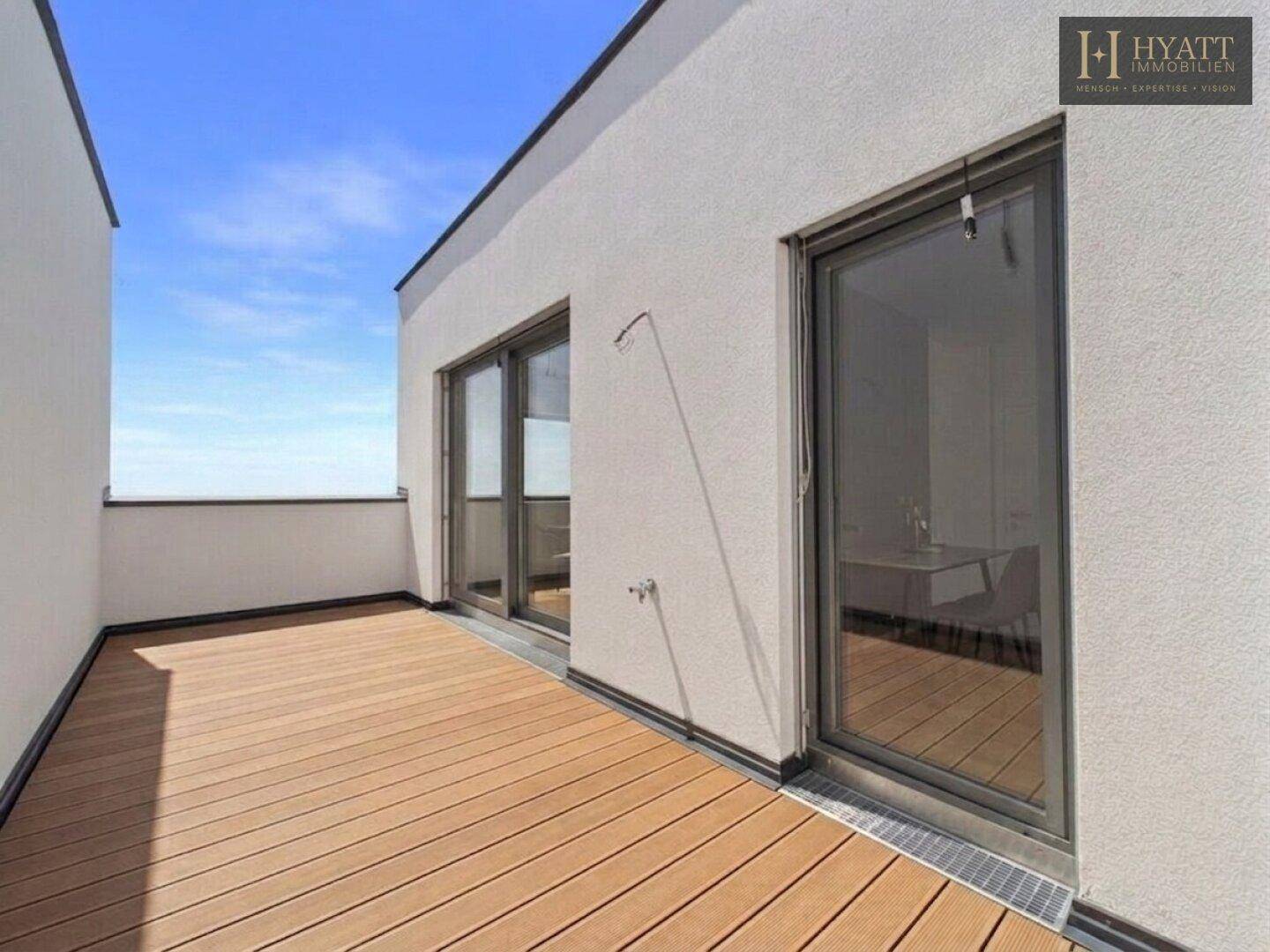Große Dachterrasse mit Holzdielenboden und weitem Blick über die grüne Umgebung.