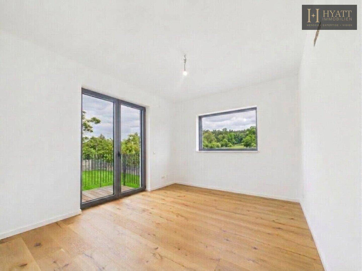 Helles Schlafzimmer mit Holzboden, Fenster und Zugang zu einem französischen Balkon.