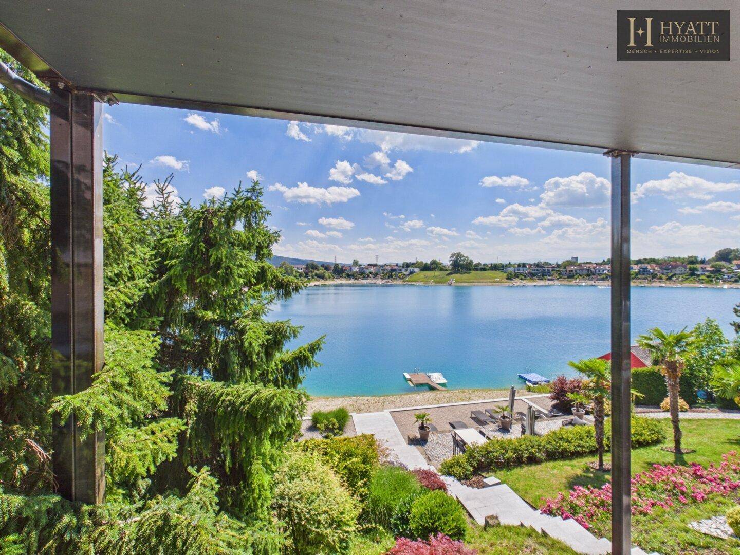 Überdachte Terrasse mit weitem Blick auf den See und die üppige grüne Umgebung.