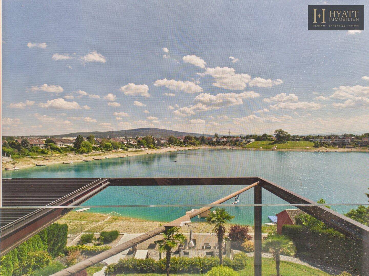 Panoramablick auf den See mit blauem Himmel und umliegender Landschaft von der Terrasse.