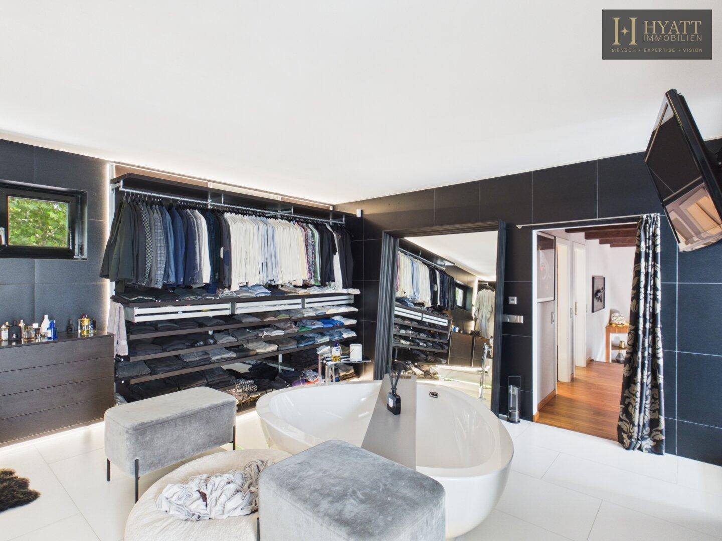 Offenes Badezimmer mit freistehender Badewanne und integriertem begehbarem Kleiderschrank.