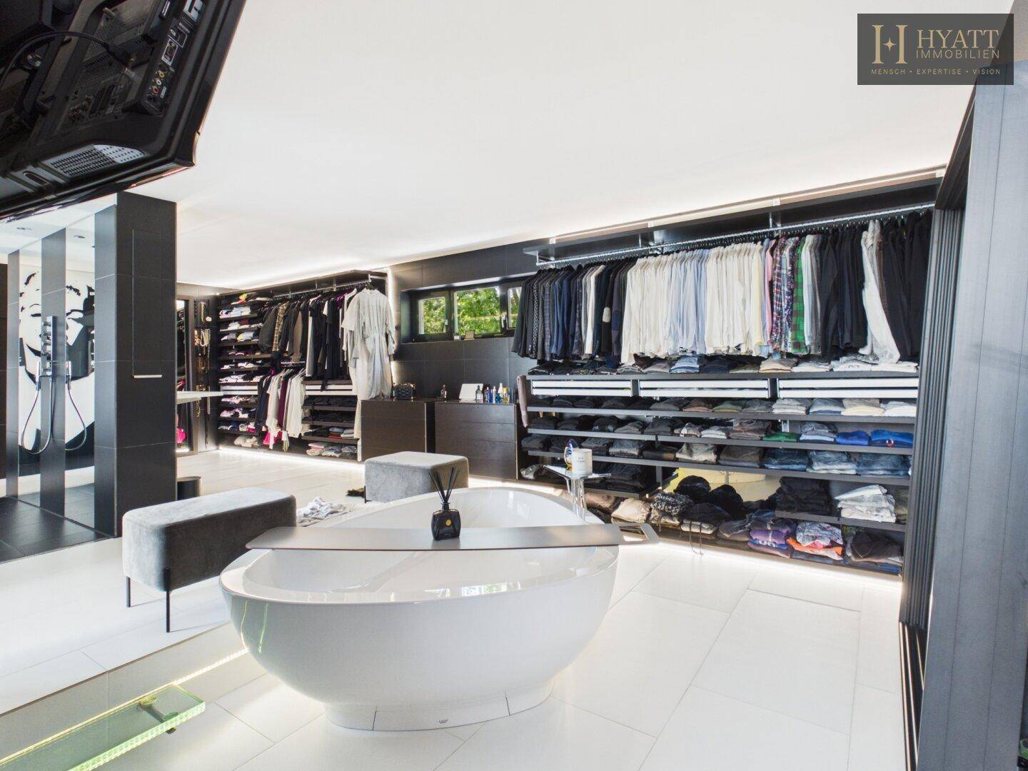 Geräumiger begehbarer Kleiderschrank mit integrierter Badewanne und viel Stauraum.