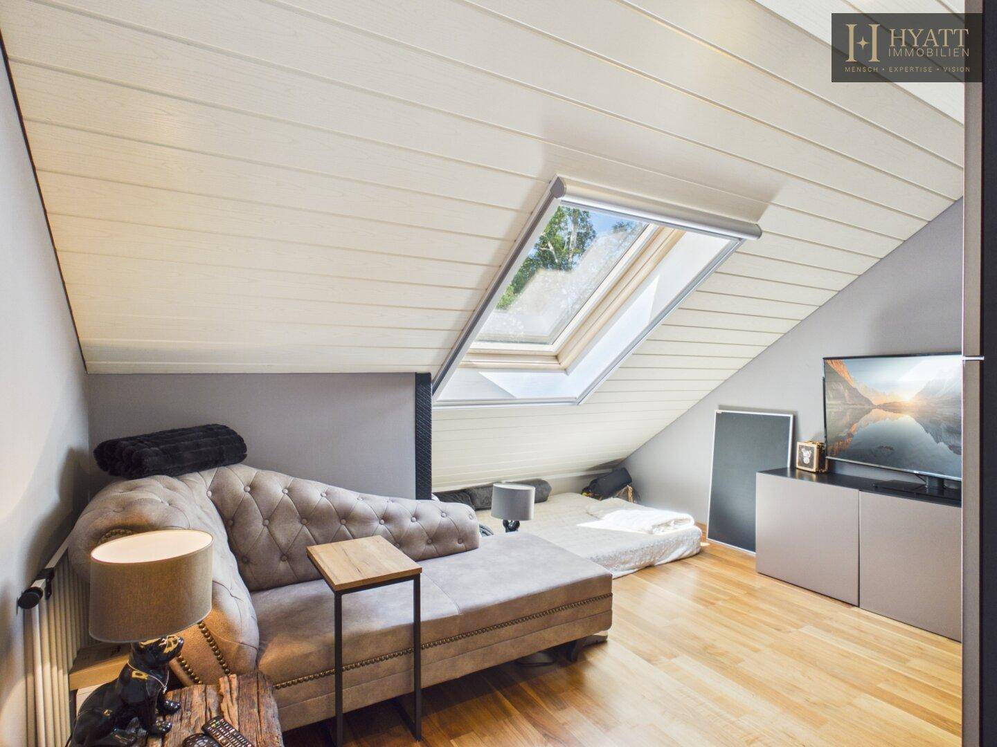 Gemütliches Schlafzimmer im Dachgeschoss mit Dachschräge, Holzboden und Dachfenster.