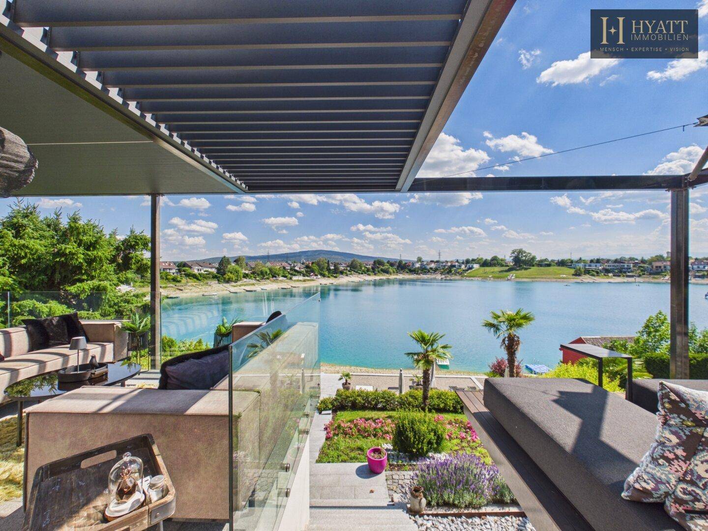 Großzügige Terrasse mit Loungemöbeln und spektakulärem Panoramablick auf den See.