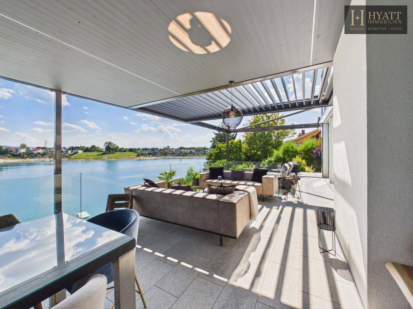 Geräumige überdachte Terrasse mit Lounge- und Essbereichen und spektakulärem Seepanorama.