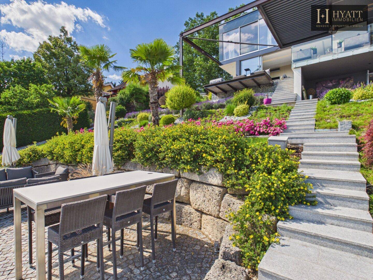 Moderne Architektur des Hauses mit Terrassen, Treppen und aufwendiger Gartengestaltung am See.