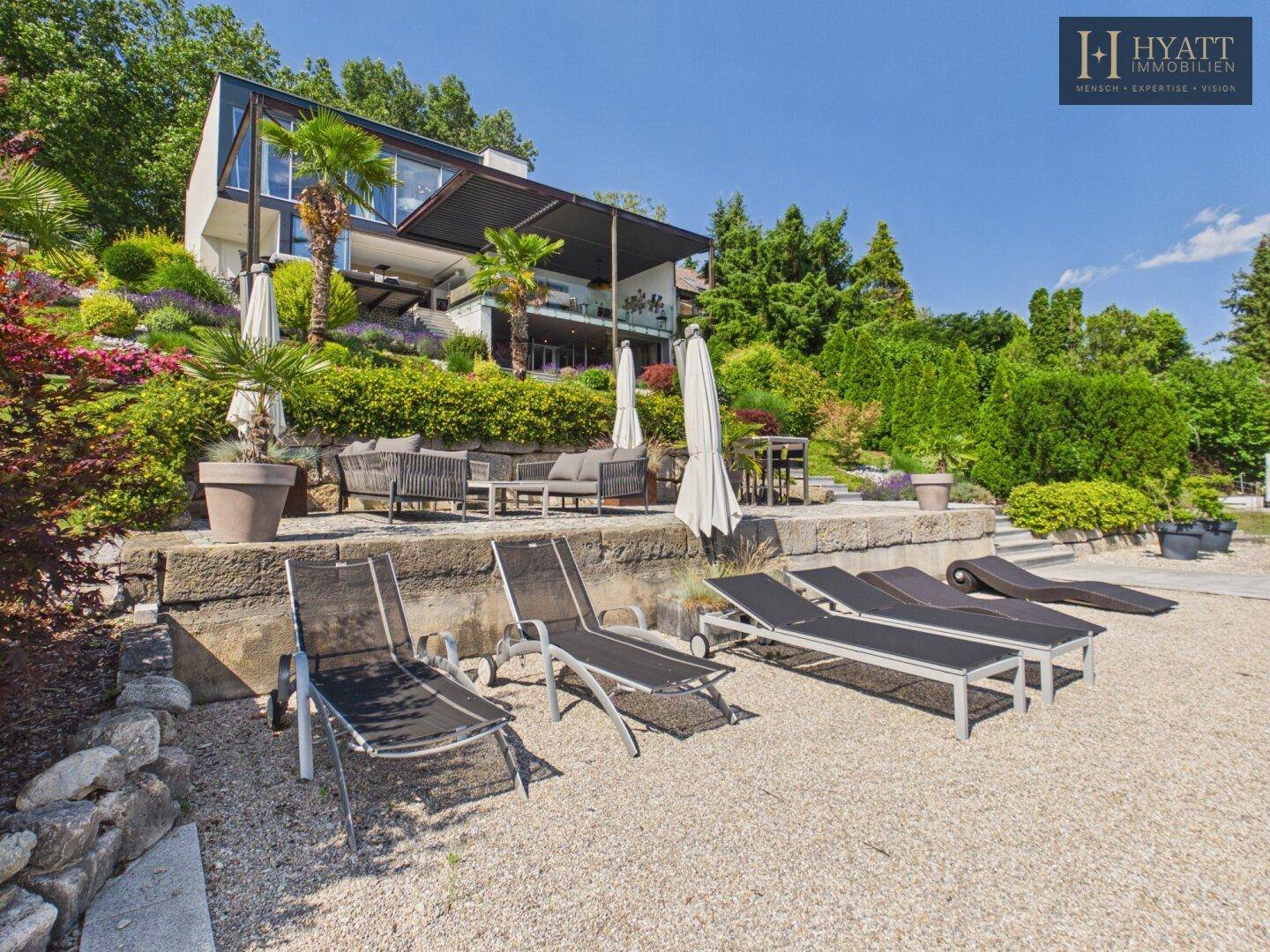 Exklusive Villa mit großzügiger Terrasse, Liegestühlen und direktem Zugang zum Seeufer.