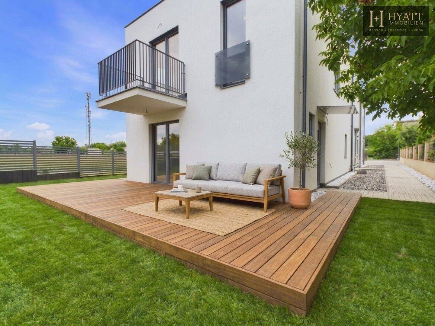 Geräumige Holzterrasse mit bequemer Lounge-Sitzgruppe und Blick auf den grünen Garten.