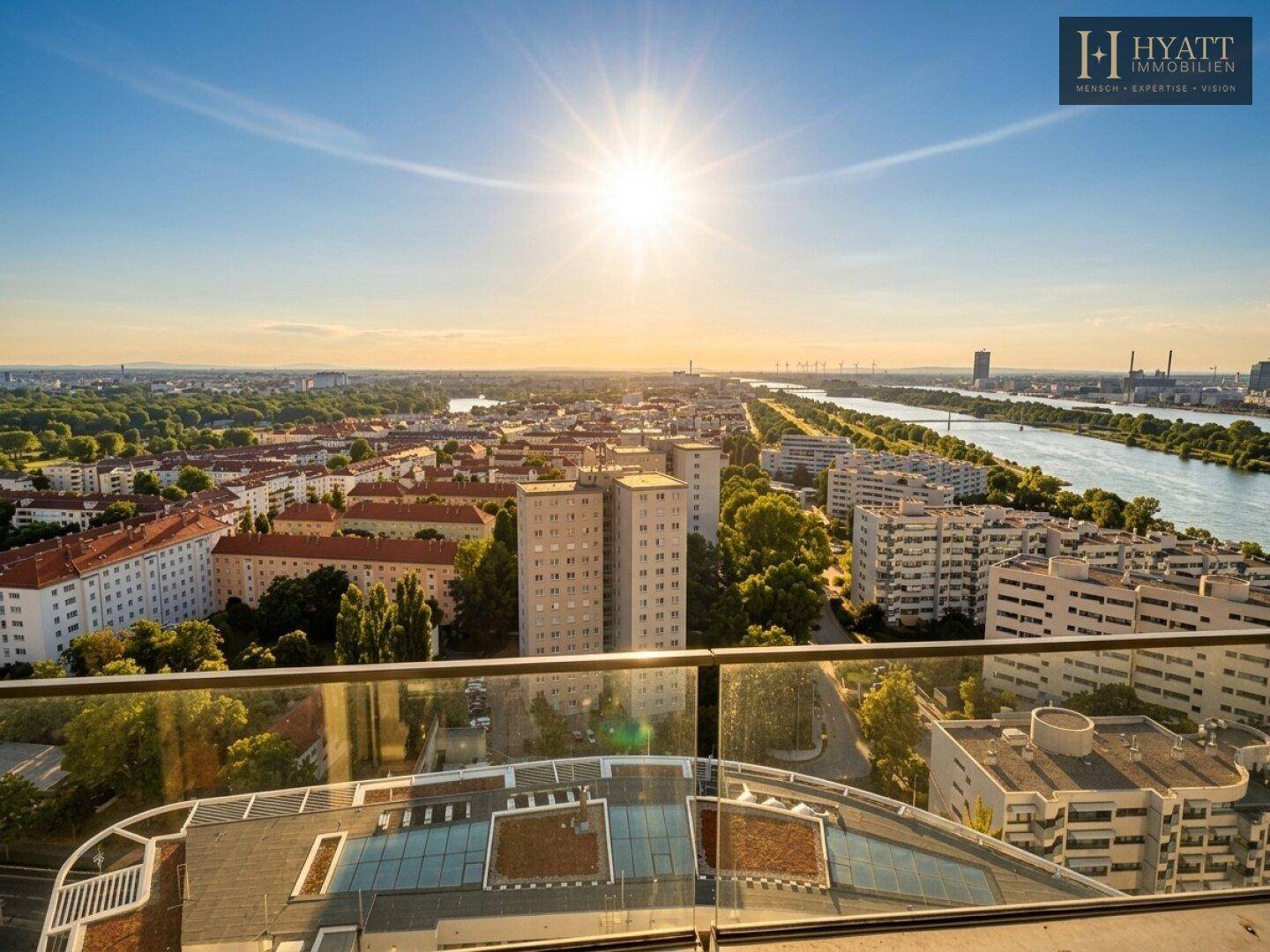 Panoramablick von einem Hochhausbalkon bei Sonnenuntergang über die Stadt und den Fluss.