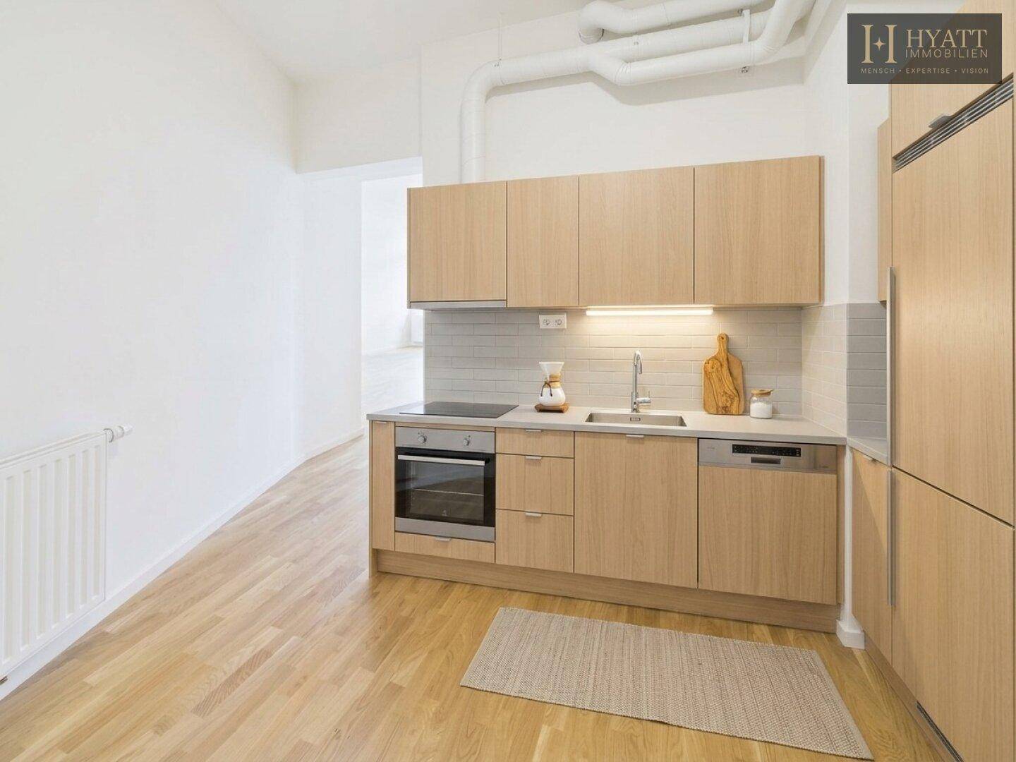 Funktionale Küche mit hellen Holzfronten, integrierten Geräten und Parkettboden, bereit zum Kochen.