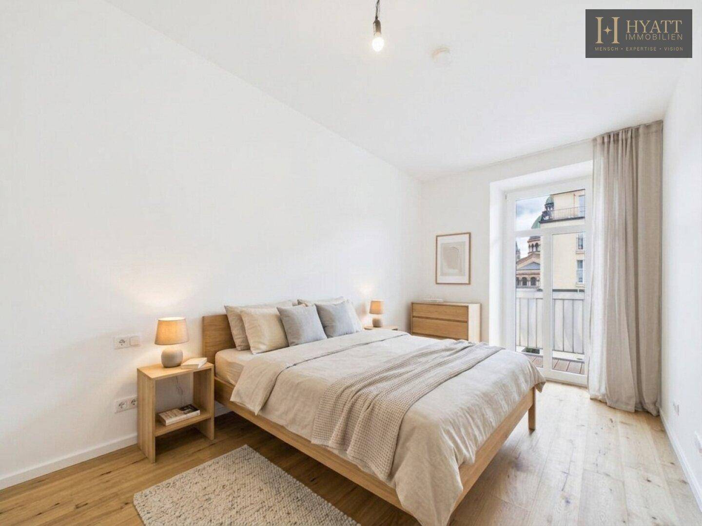 Helles Schlafzimmer mit Holzbett, Nachttischen und Zugang zu einem französischen Balkon.