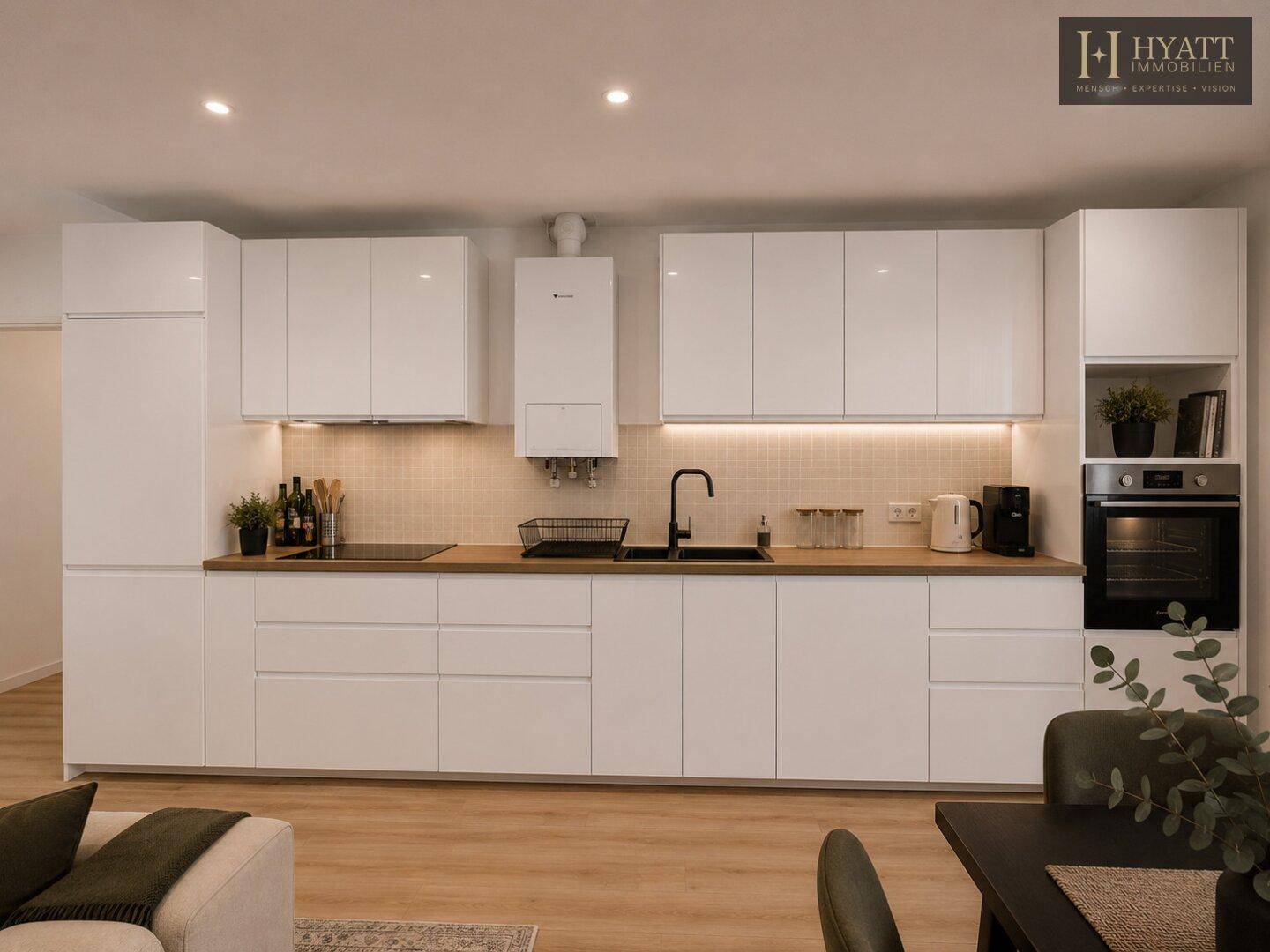 Moderne Einbauküche mit weißen Hochglanzfronten, Holz-Arbeitsplatte und integriertem Backofen.