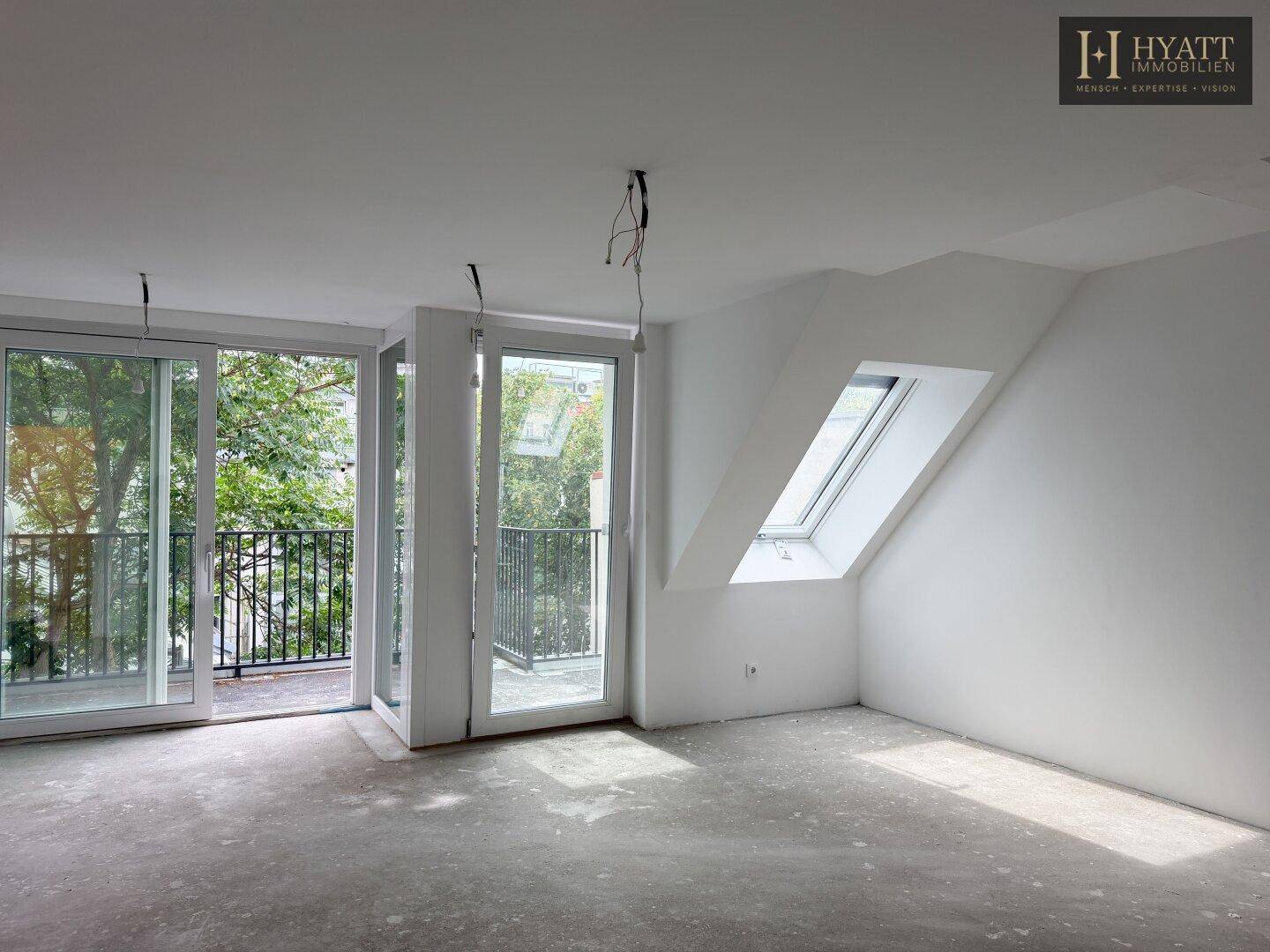Heller, unmöblierter Raum im Rohbau mit großen Fenstern und einem Dachfenster.