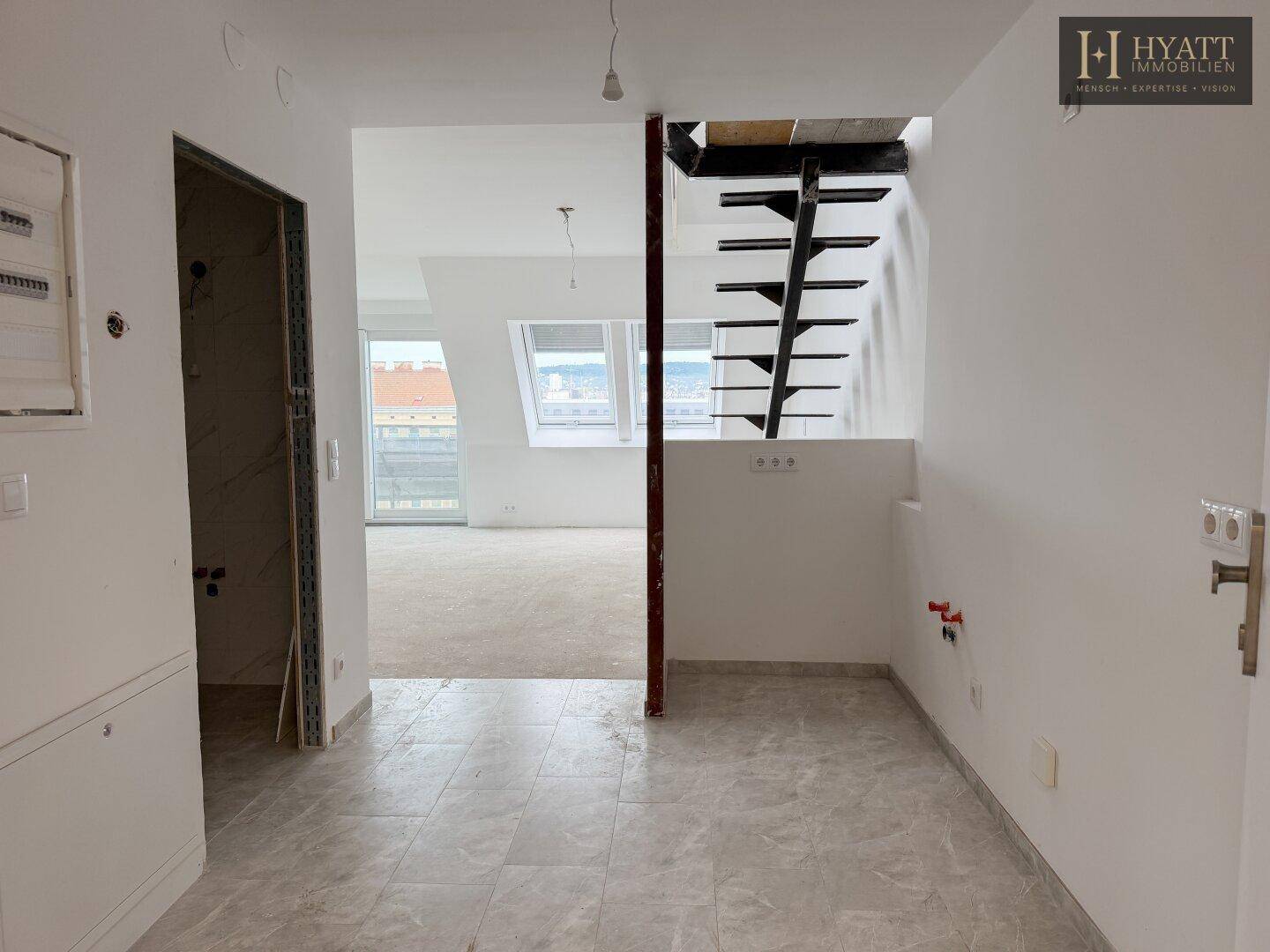 Eingangsbereich mit Fliesenboden und Blick auf den offenen Wohnbereich mit Treppe.