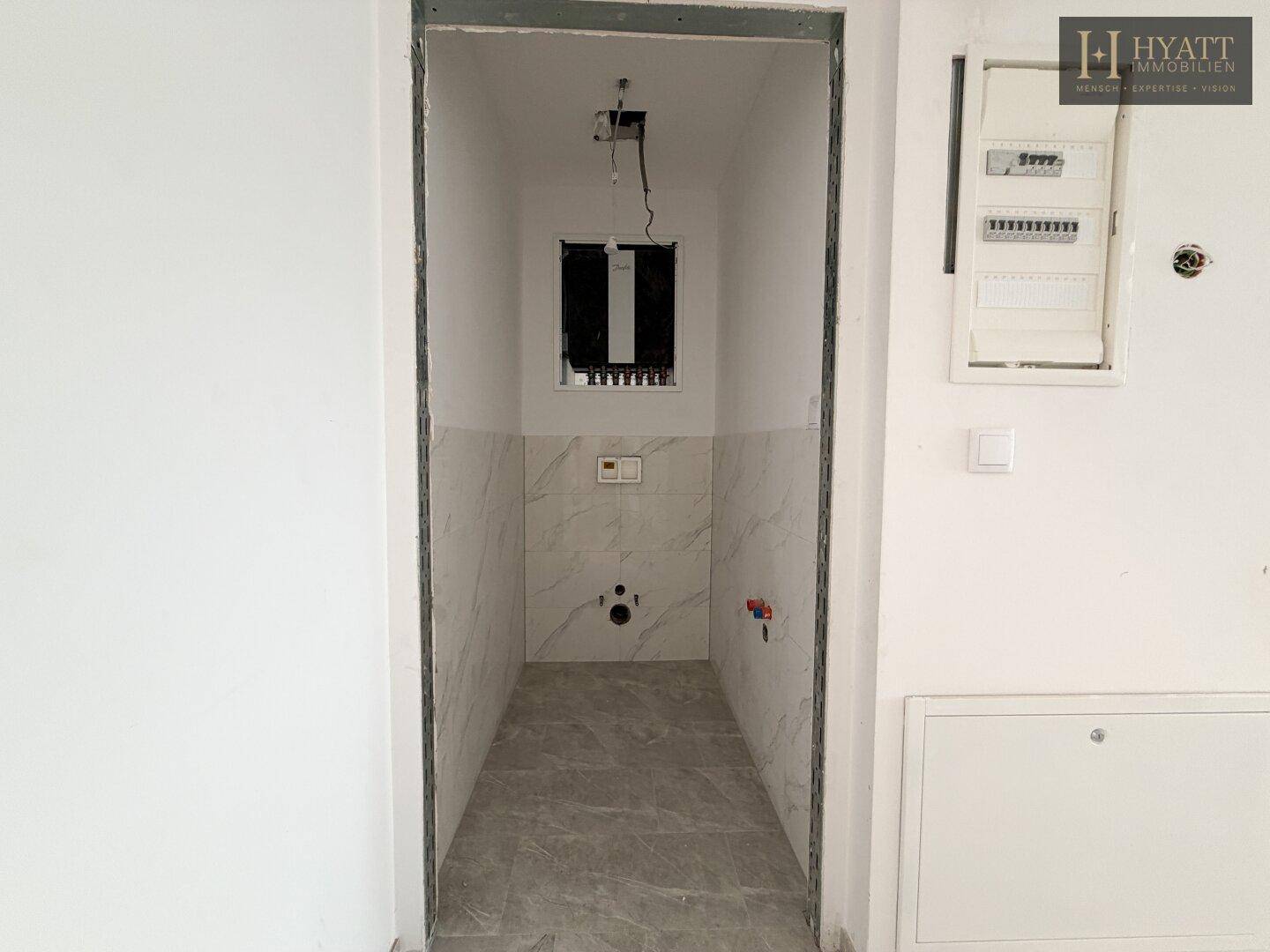 Unfertiges Gäste-WC mit Fliesen an Wänden und Boden, bereit für die Installation der Sanitärobjekte.