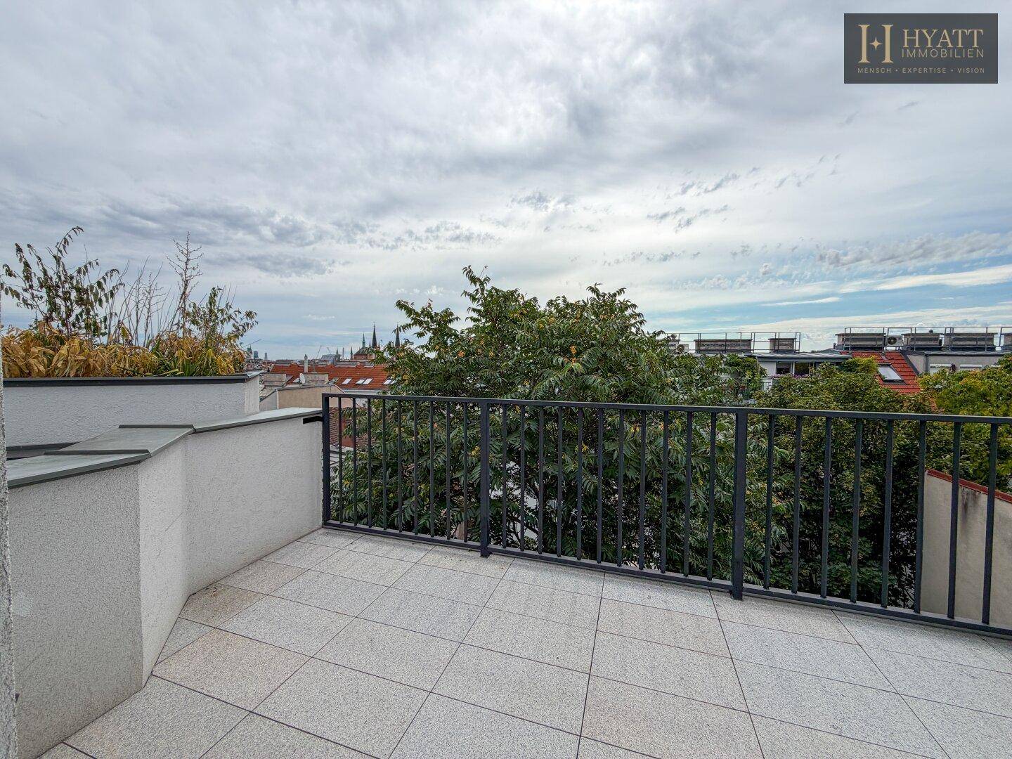 Weitläufige Dachterrasse mit Fliesenboden und freiem Blick auf die umliegende Stadtlandschaft.