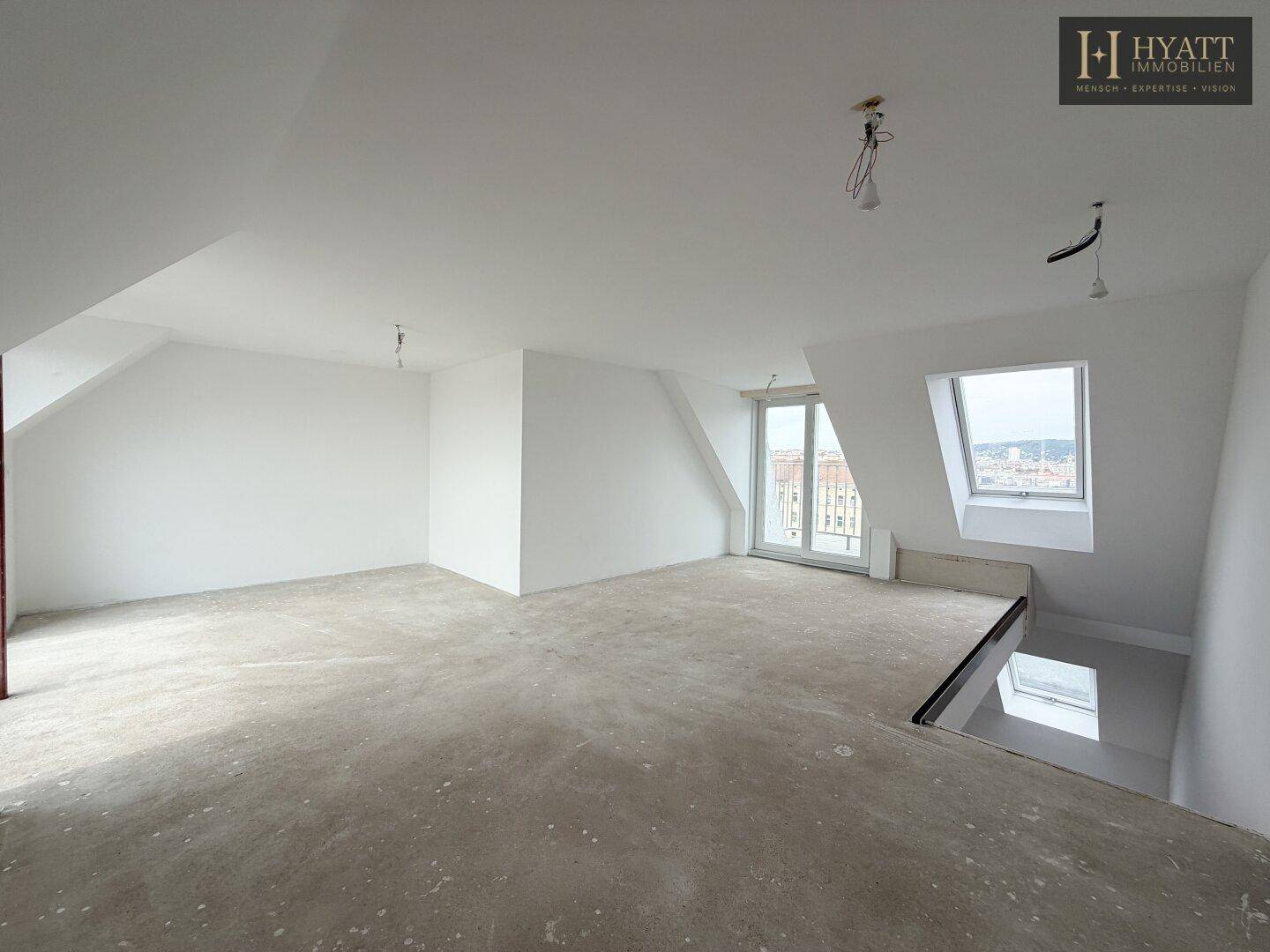 Unmöblierter Raum im Dachgeschoss mit Dachschrägen und Zugang zu einem Balkon.