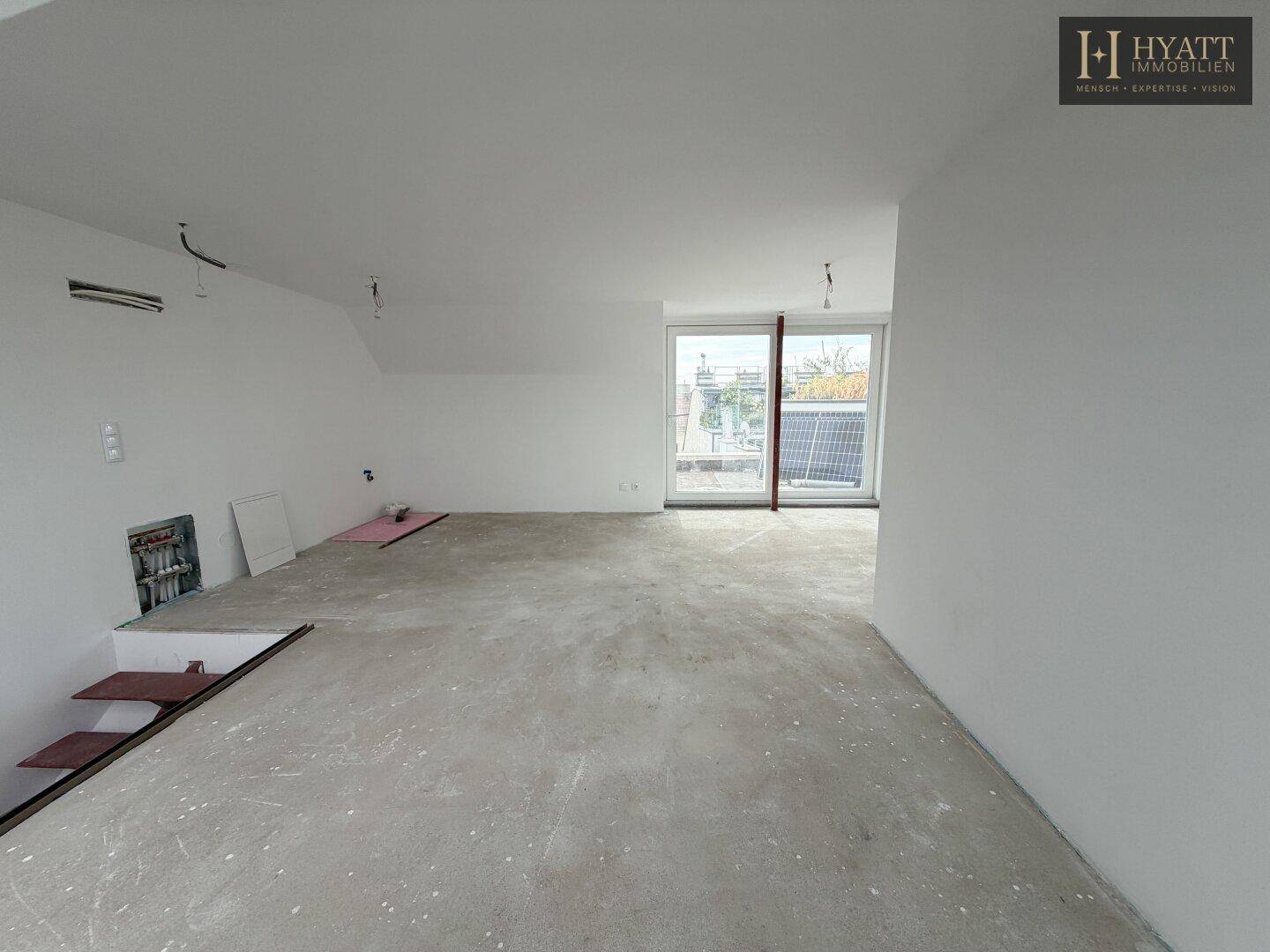 Großer, unmöblierter Raum mit Zugang zu einer Terrasse und Blick auf die Umgebung.