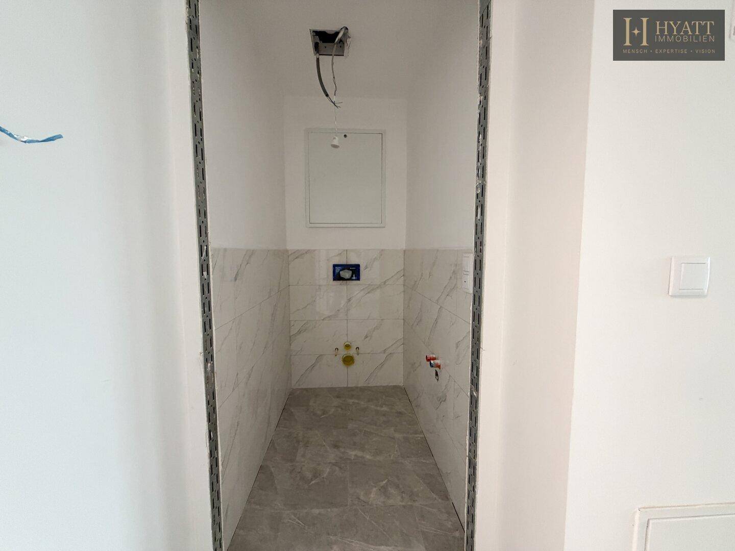 Unfertiges Gäste-WC mit Marmorfliesen an den Wänden und auf dem Boden, bereit für die Installation.