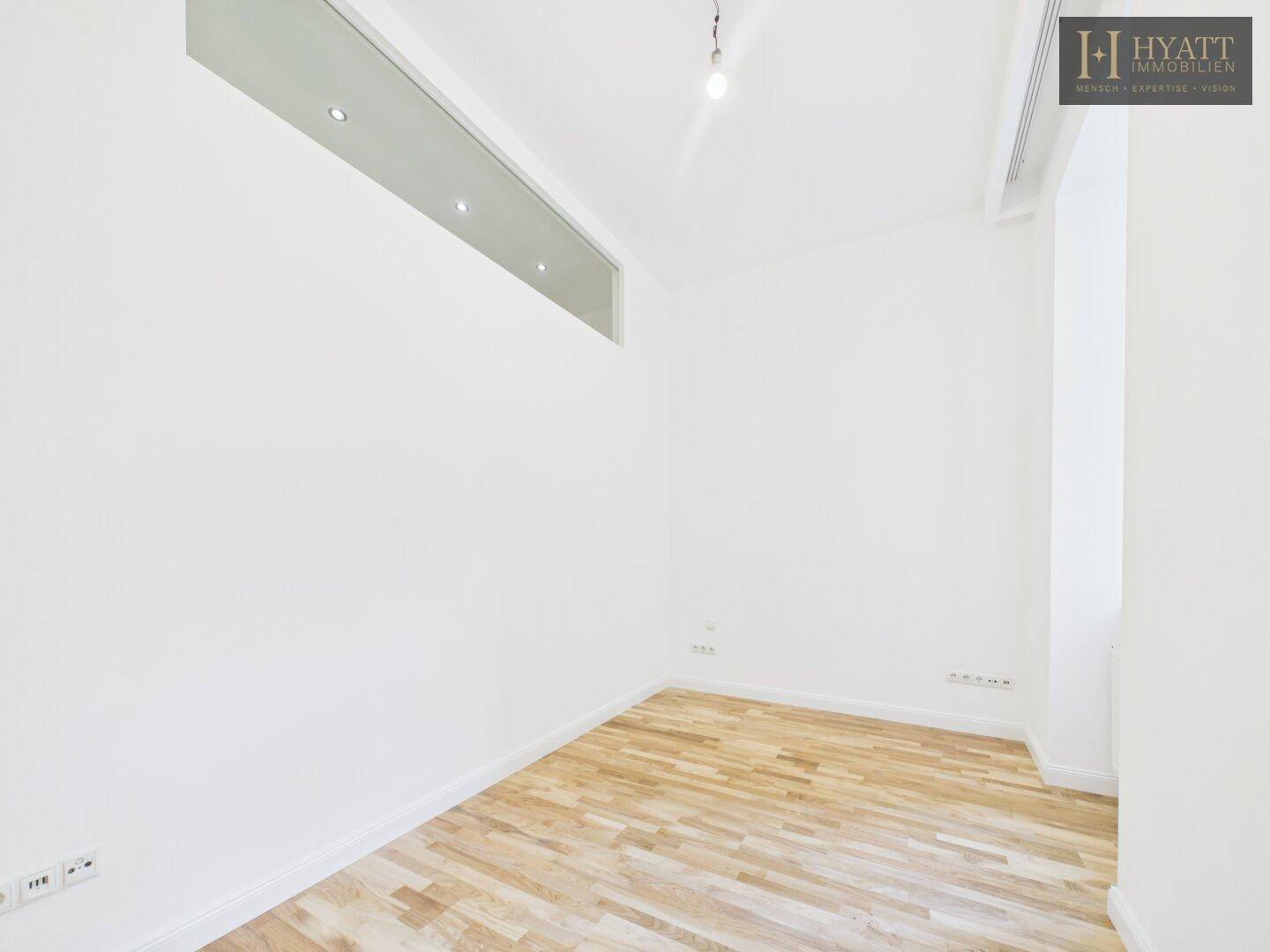 Kleines, helles Zimmer mit Parkettboden und einer Oberlichte für zusätzliches Licht.