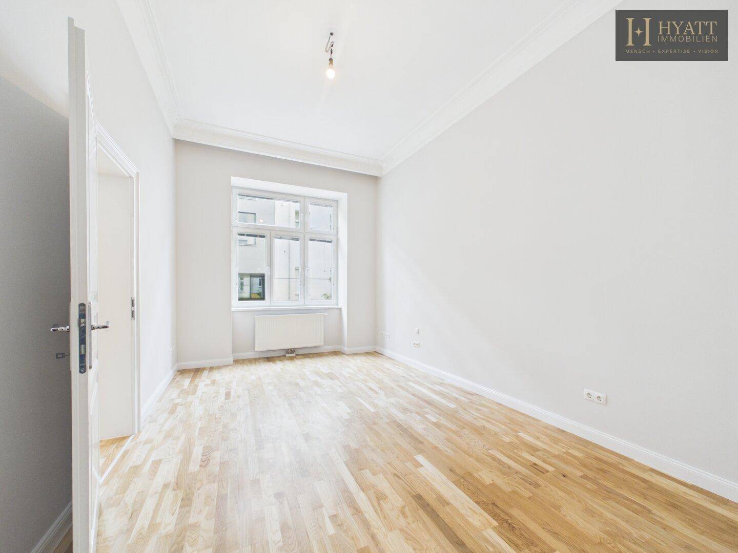 Helles Zimmer mit Parkettboden und einem Fenster, bereit für individuelle Gestaltung.