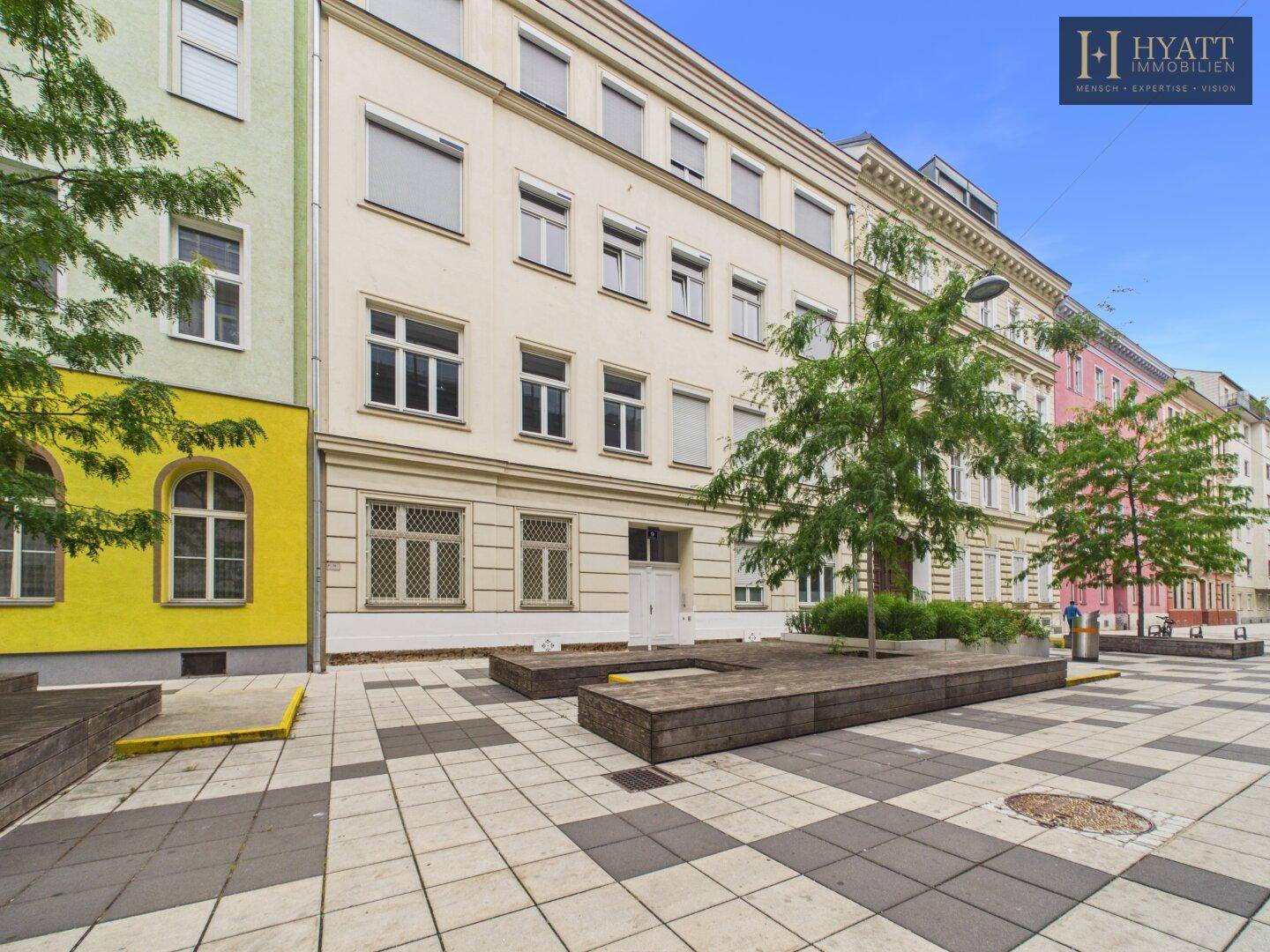 Historische Fassade eines Wohngebäudes mit klassischer Architektur und großen Fenstern.