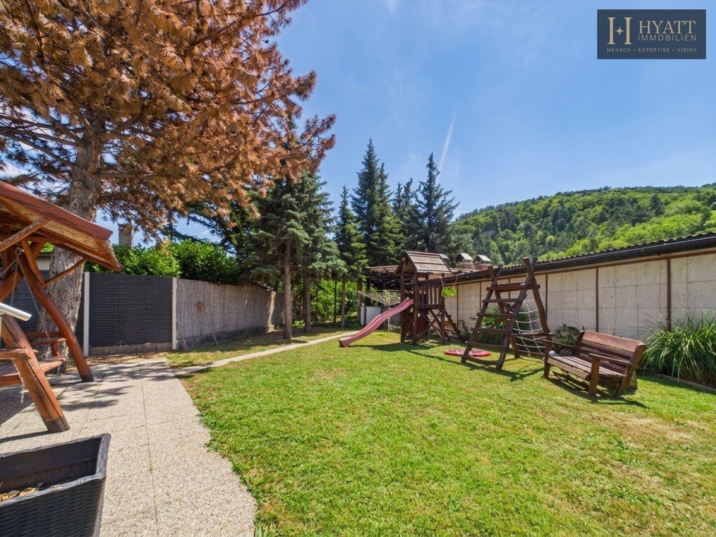 Großer Garten mit Rasenfläche, Spielplatz und altem Baumbestand.