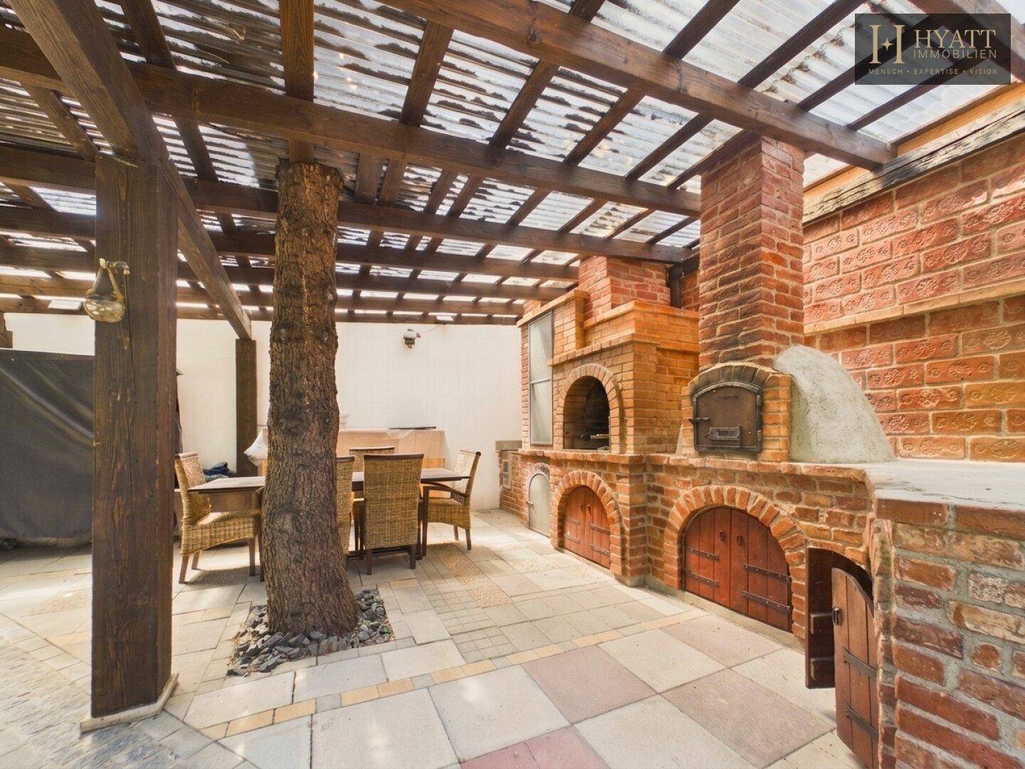 Überdachte Terrasse mit gemauertem Grillbereich und Essplatz im Freien.
