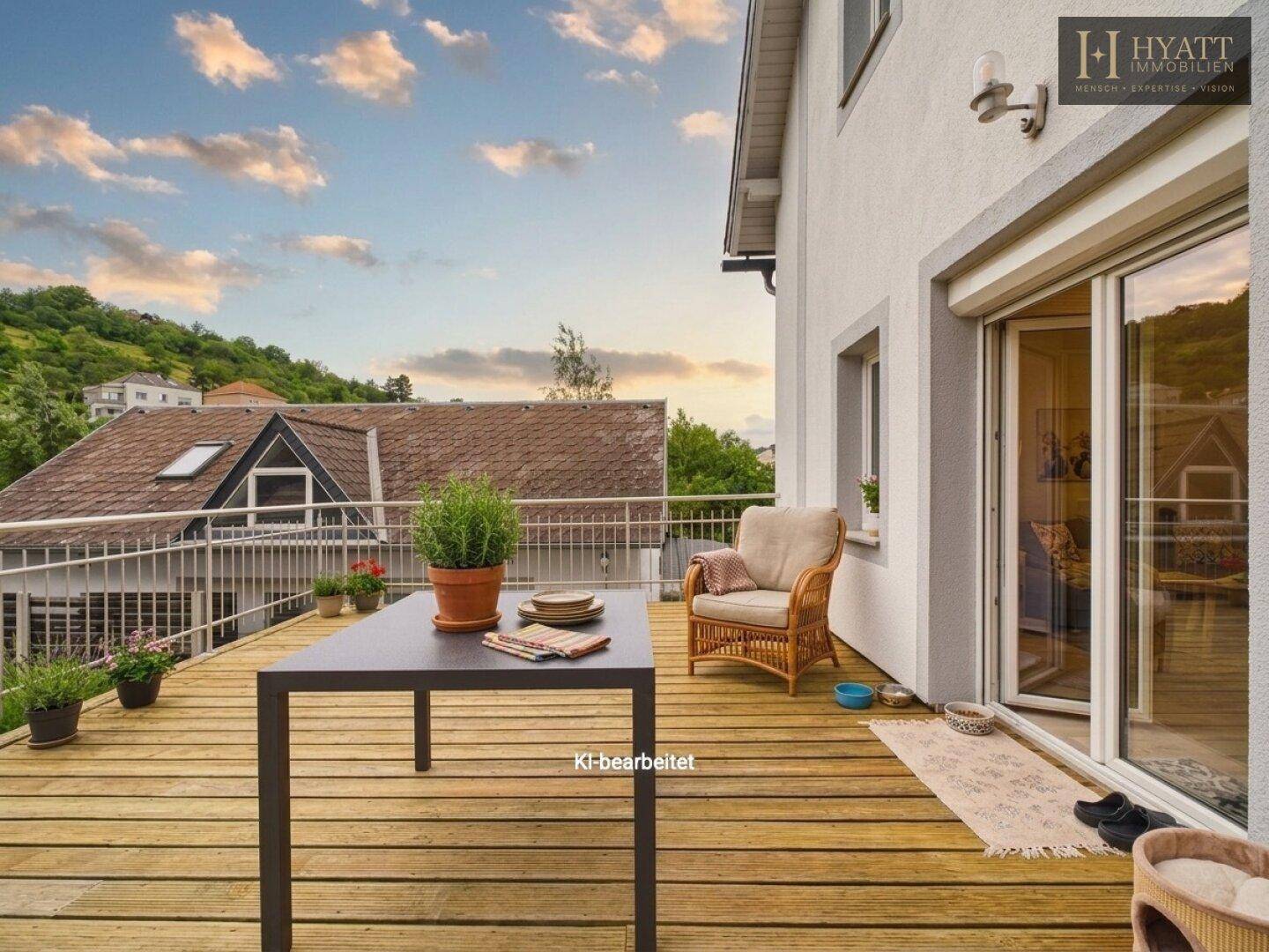 Holzterrasse mit Sitzgelegenheiten und weitem Blick auf die umliegende Landschaft.