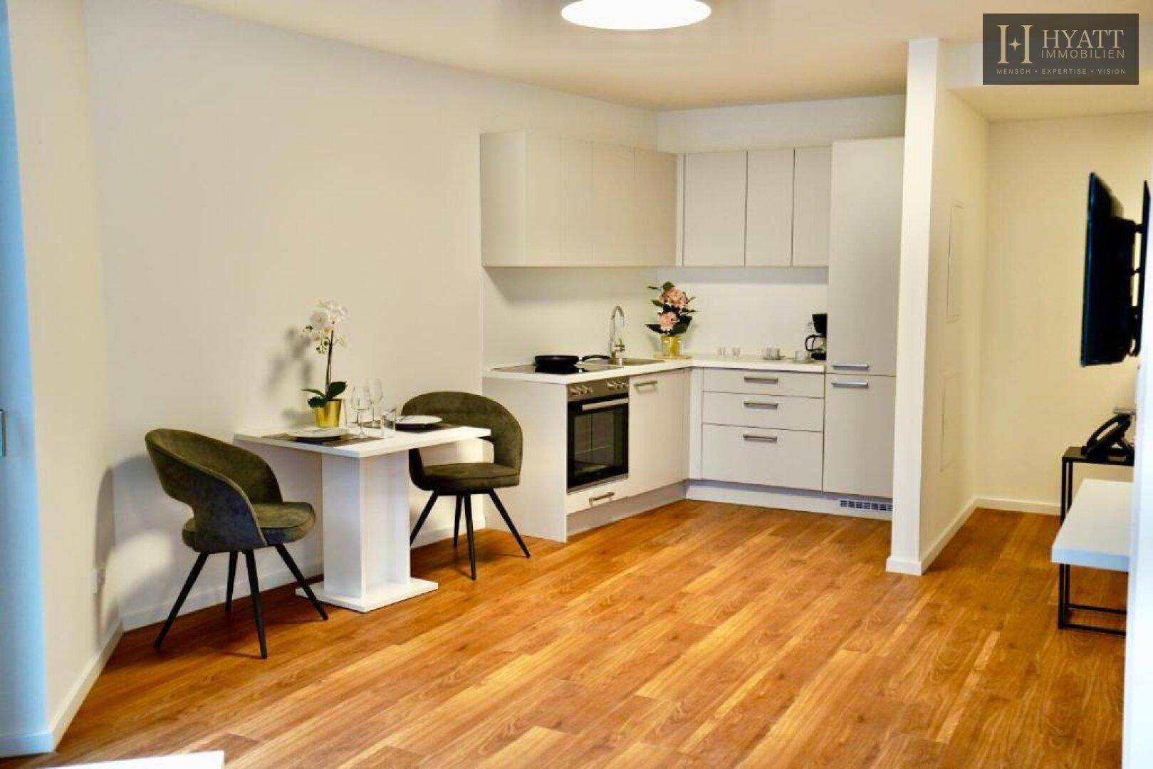 Helle Küchenzeile mit Essbereich und Holzboden in einem modernen Apartment.