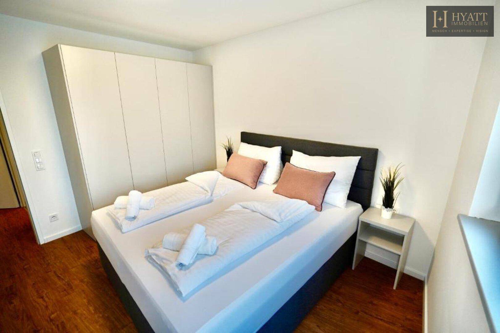 Modernes Schlafzimmer mit Doppelbett, Einbauschrank und Holzboden.