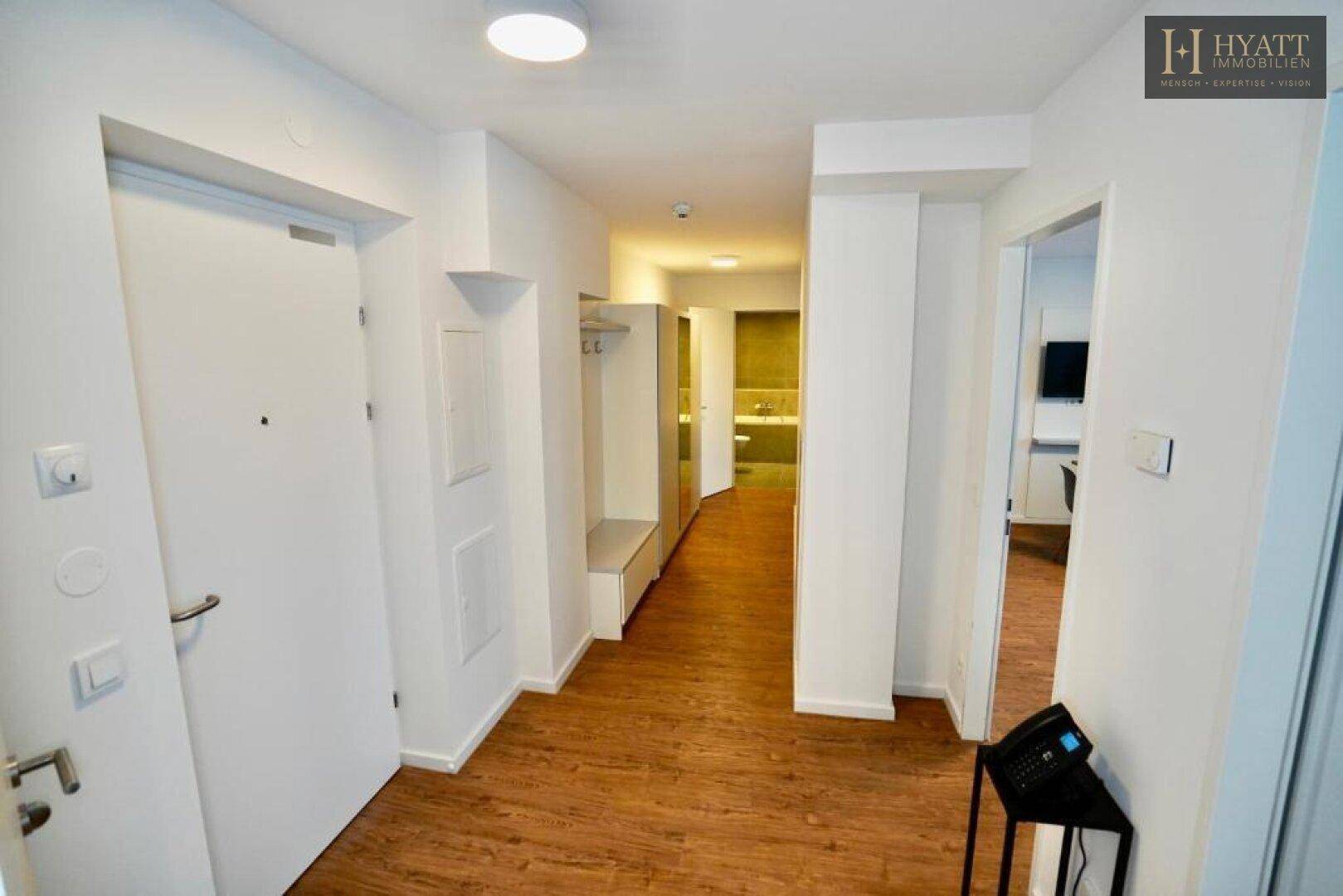 Heller Flur mit Garderobe und Holzboden, der zu weiteren Räumen führt.