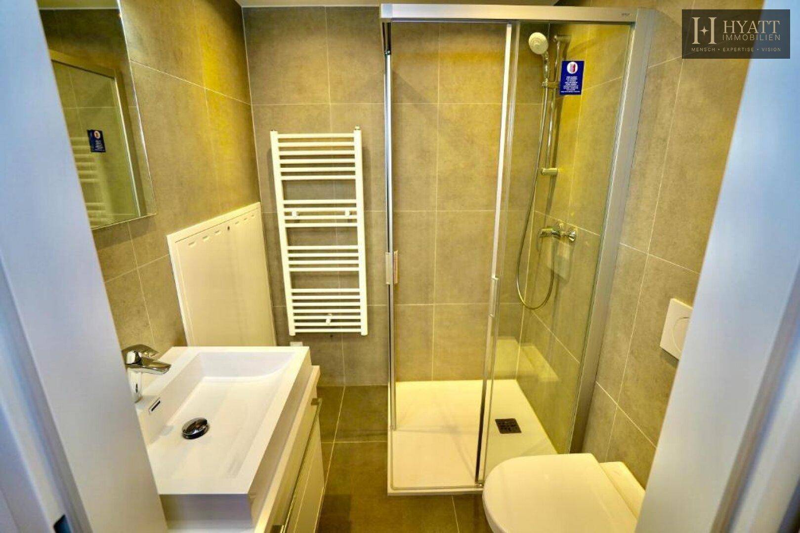 Modernes Badezimmer mit Dusche, Waschbecken und beheiztem Handtuchhalter.
