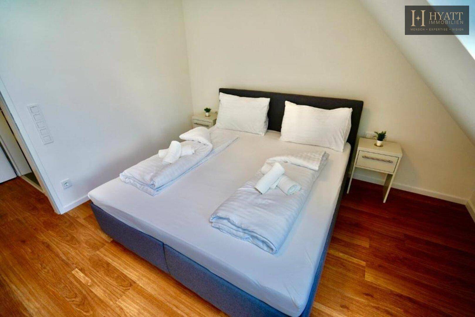 Gemütliches Schlafzimmer mit Holzboden und schräger Decke, ideal für erholsame Nächte.