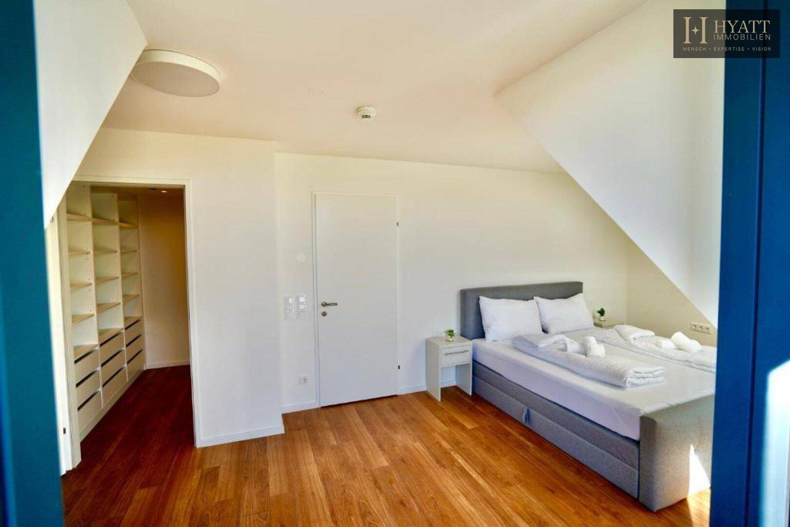 Schlafzimmer mit Holzboden und direktem Zugang zu einem begehbaren Kleiderschrank.